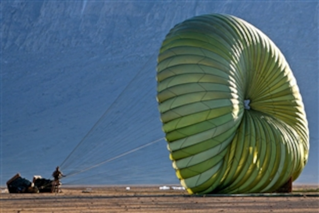 A U.S. Marine holds onto a parachute attached to a supply of water and food dropped by a C-130 cargo transport aircraft during Operation Backstop in Helmand province, Afghanistan, Dec. 11, 2008. The Marines, assigned to Company I, 3rd Battalion, 8th Marine Regiment, are the ground combat element of Special Purpose Marine Air Ground Task Force – Afghanistan.
