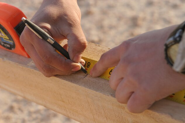 Cpl. Emilio Avalos, 20, from El Paso, Texas, an engineer with General Support Platoon, Company B, 1st Combat Engineer Battalion, Regimental Combat Team 5, marks where he must make precision cuts that will serve as braces for the wooden hut he and his fellow engineers are building near the city of Haditha, Iraq, Dec 15. This was the first time any of the engineers had built this particular type of hut, but thanks to their training and general knowledge of carpentry, they were able to finish the project two days ahead of schedule. ::r::::n::