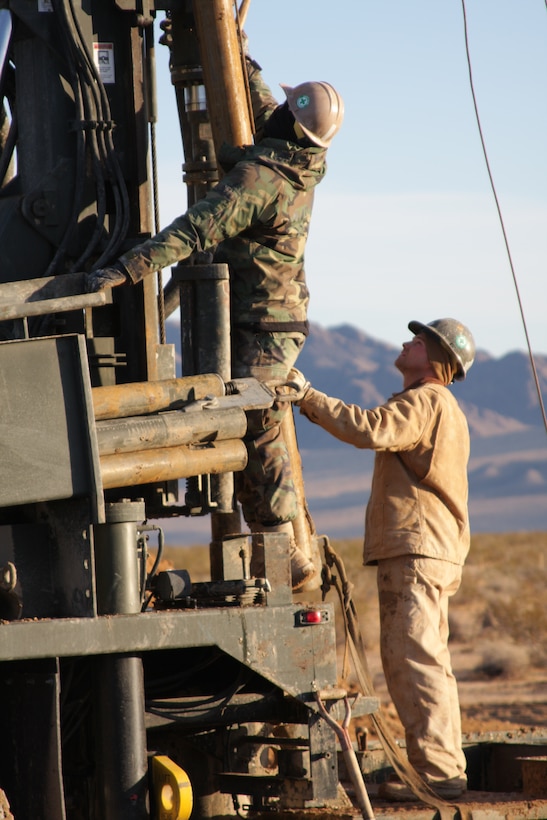 Petty Officer 2nd Class Dillon Weiderman and Petty Officer 1st Class Justin Richards, equipment operators with the Naval Mobile Construction Battalion 40 drilling team from Naval Base Ventura County, Port Hueneme, Calif., erect a drill tower for work at the Combat Center’s West training area Tuesday, Dec. 16, 2008. The Seabees are helping the Public Works Division find hot spots for geothermal energy in the West training area, which can be used to support the base and cut down energy usage. Weiderman, a Michigan native, slides a piece of the drill in place while Richards, a Brainerd, Minn, native, acts as a second set of eyes to make sure the work is completely safely.