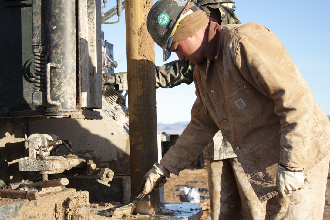 Petty Officer 1st Class Justin Richards, an equipment operator with the Naval Mobile Construction Battalion 40 drilling team from Naval Base Ventura County, Port Hueneme, Calif., erect a drill tower for work at the Combat Center’s West training area Tuesday, Dec. 16, 2008. The Seabees are helping the Public Works Division find hot spots for geothermal energy in the West training area, which can be used to support the base and cut down energy usage. Richards, a Brainerd, Minn., native cleans mud off the base of the drill so it doesn’t jam.