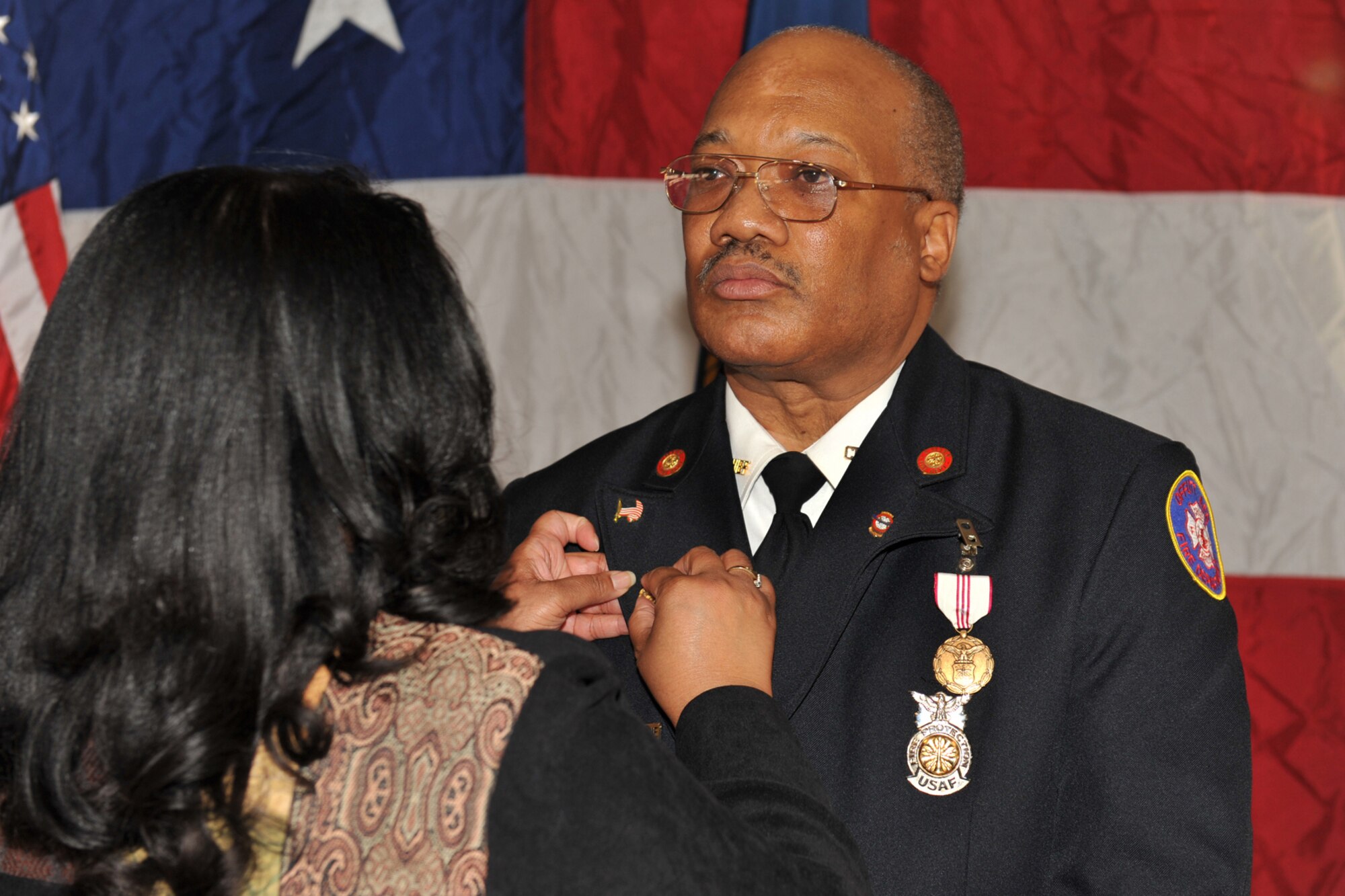 OFFUTT AIR FORCE BASE, Neb. - Barbara Gullie presents her husband, Fire Chief Robin Gullie, 55th Civil Engineering Squadron, his retirement pin. After 38 years of service, and many distinguished awards he retires Dec. 12. (Photo By: Charles Haymond).