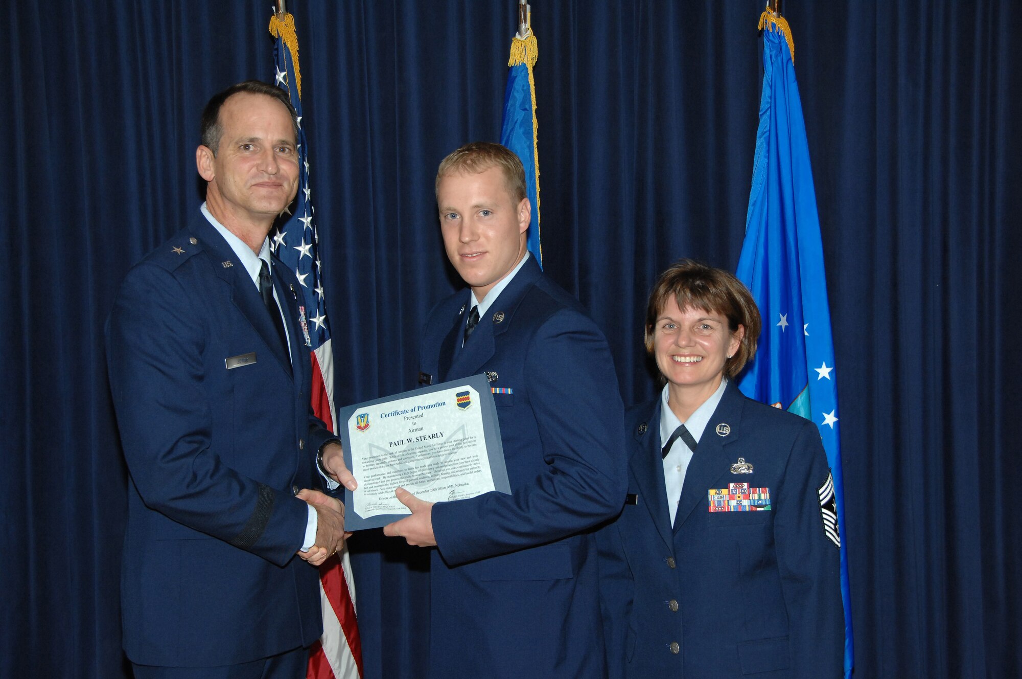 OFFUTT AIR FORCE BASE, Neb. -- 55th Wing Commander Brig. Gen. James Jones, left, and 55th Wing Commmand Chief Master Sgt. Lisa A. Sirois, right, congratulate  Airman Paul W. Stearly, 55th Aircraft Maintenance Squadron, on his promotion at the Patriot Club Dec. 4. The promotion ceremony was held to promote and recognize all promotees in the elisted ranks at Offutt. (U.S. Air Force Photo by Dana P. Heard)