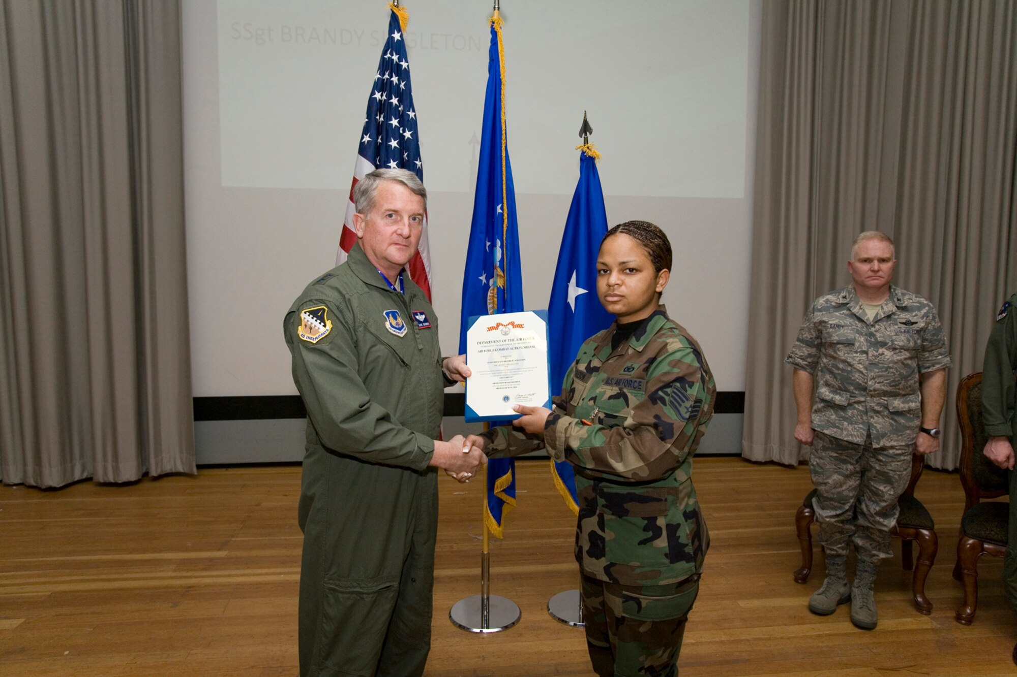 Staff Sgt. Brandy Singleton, with the 95th Security Forces Squadron, receives an Air Force Combat Action Medal from Maj. Gen. David Eichhorn, Air Force Flight Test Center commander, during an award ceremony at base theater Dec. 12. The medal is awarded to Airmen for active participation in combat, having been under direct and hostile fire or physically engaging hostile forces with direct and lethal fire, in connection with military operations while serving with Operation Iraqi Freedom. (Air Force photo by Jet Fabara)