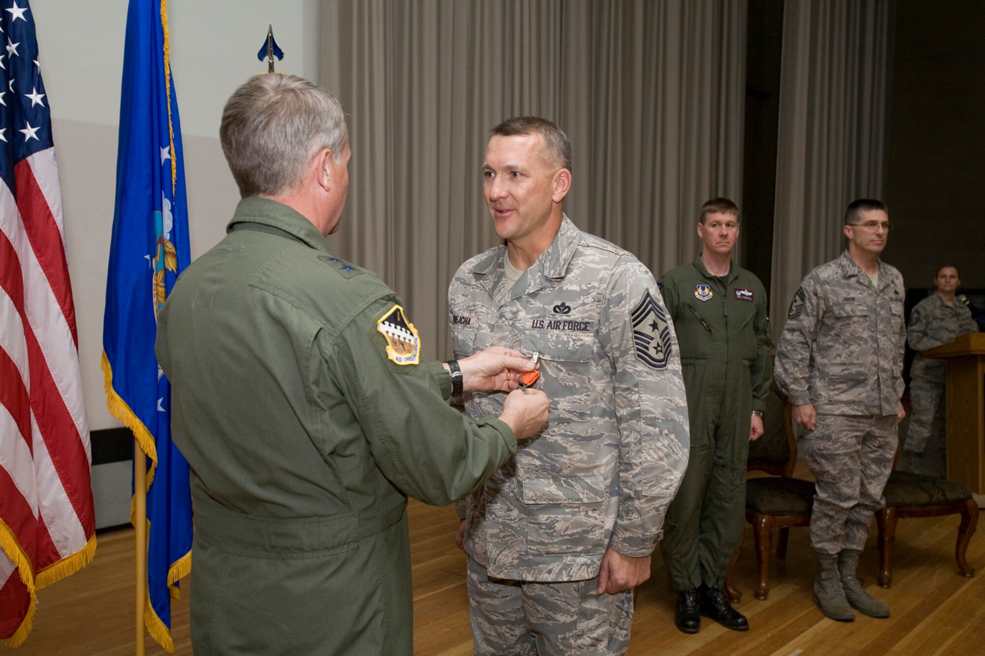 Chief Master Sgt. Mark Brejcha, 412th Test Wing command chief, receives an Air Force Combat Action Medal from Maj. Gen. David Eichhorn, Air Force Flight Test Center commander, during an award ceremony at base theater Dec. 12. The medal is awarded to Airmen for active participation in combat, having been under direct and hostile fire or physically engaging hostile forces with direct and lethal fire, in connection with military operations while serving with Operation Iraqi Freedom. (Air Force photo by Jet Fabara)