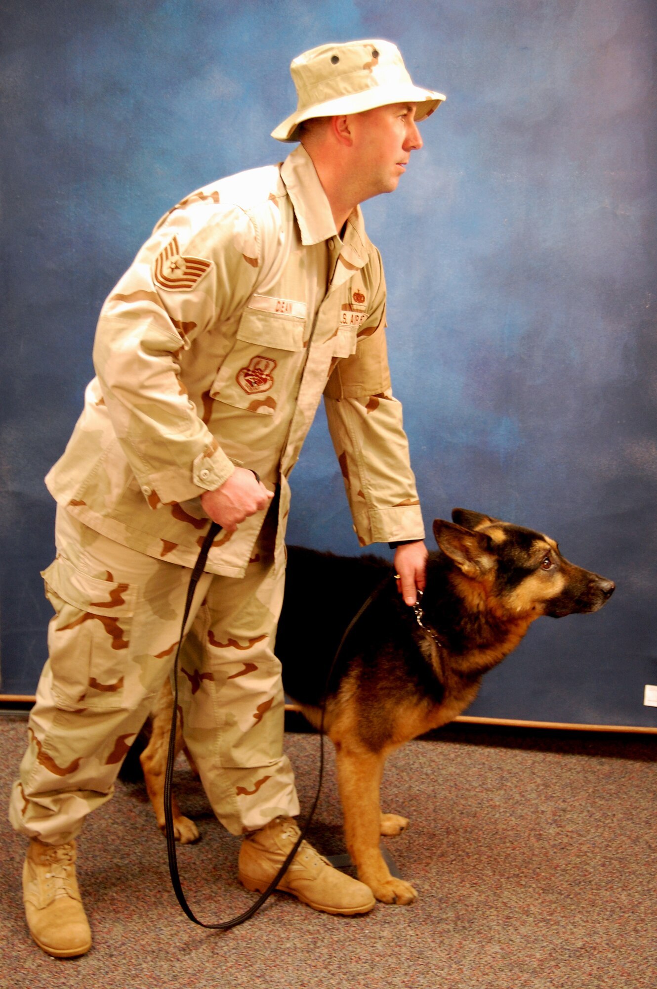 Tech. Sgt. Jeff Dean, security forces contingency skills instructor with the U.S. Air Force Expeditionary Center's 421st Combat Training Squadron, models for a photo Dec. 11, 2008, with military working dog Polo in the Expeditionary Center studio on Fort Dix, N.J.  The effort was part of preparatory work by an artist from the Air Force Art Program to complete a painting highlighting Expeditionary Center Airmen. (U.S. Air Force Photo/Tech. Sgt. Scott T. Sturkol)