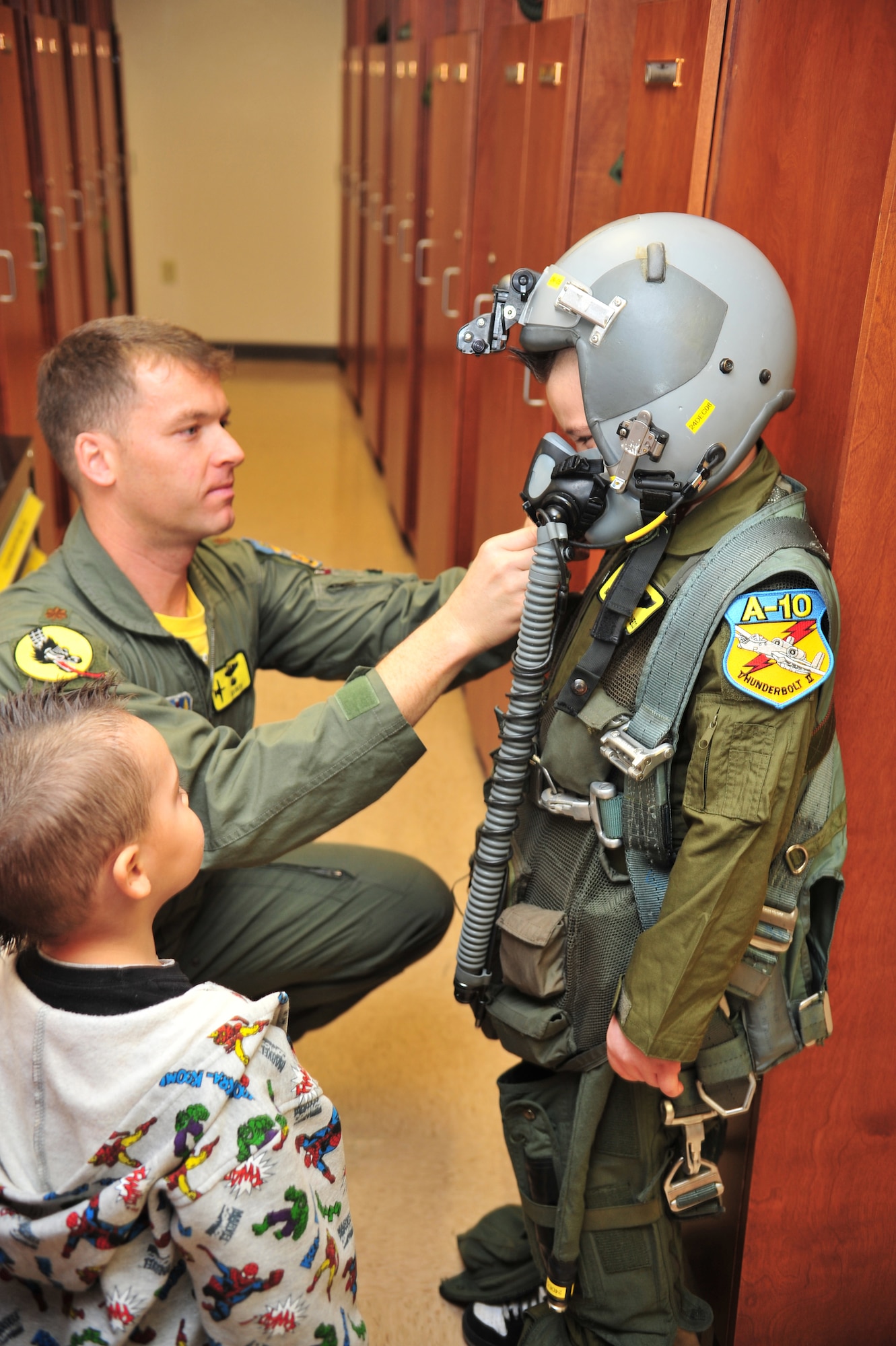 Maj. Charles "Krunch" Kistler, 357th Fighter Squadron pilot, shows Pilot For A Day Marcos Pacheco and his younger brother aircrew flight equipment during his visit to D-M, Dec. 12. The Pilot For A Day program is designed to help children with disabilities or serious illnesses enjoy a day focused on them and their interest in aviation. (U.S. Air Force photo/Senior Airman Noah R. Johnson)