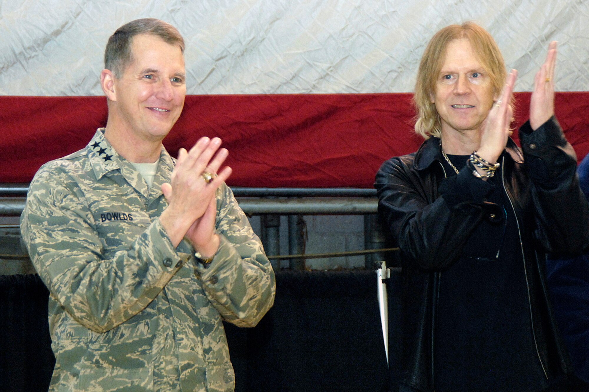 Lt. Gen. Ted Bowlds (left) and Tom Hamilton clap to the Air Force song at the conclusion of the Heroes' Homecoming celebration Dec. 12 at Hanscom Air Force Base, Mass. The event officially welcomed home more than 45 base Airmen who deployed over the past six months and paid tribute to their families. General Bowlds is the Electronic Systems Center commander. Mr. Hamilton is the bassist for the rock group Aerosmith. (U.S. Air Force photo/Linda LaBonte Britt) 
