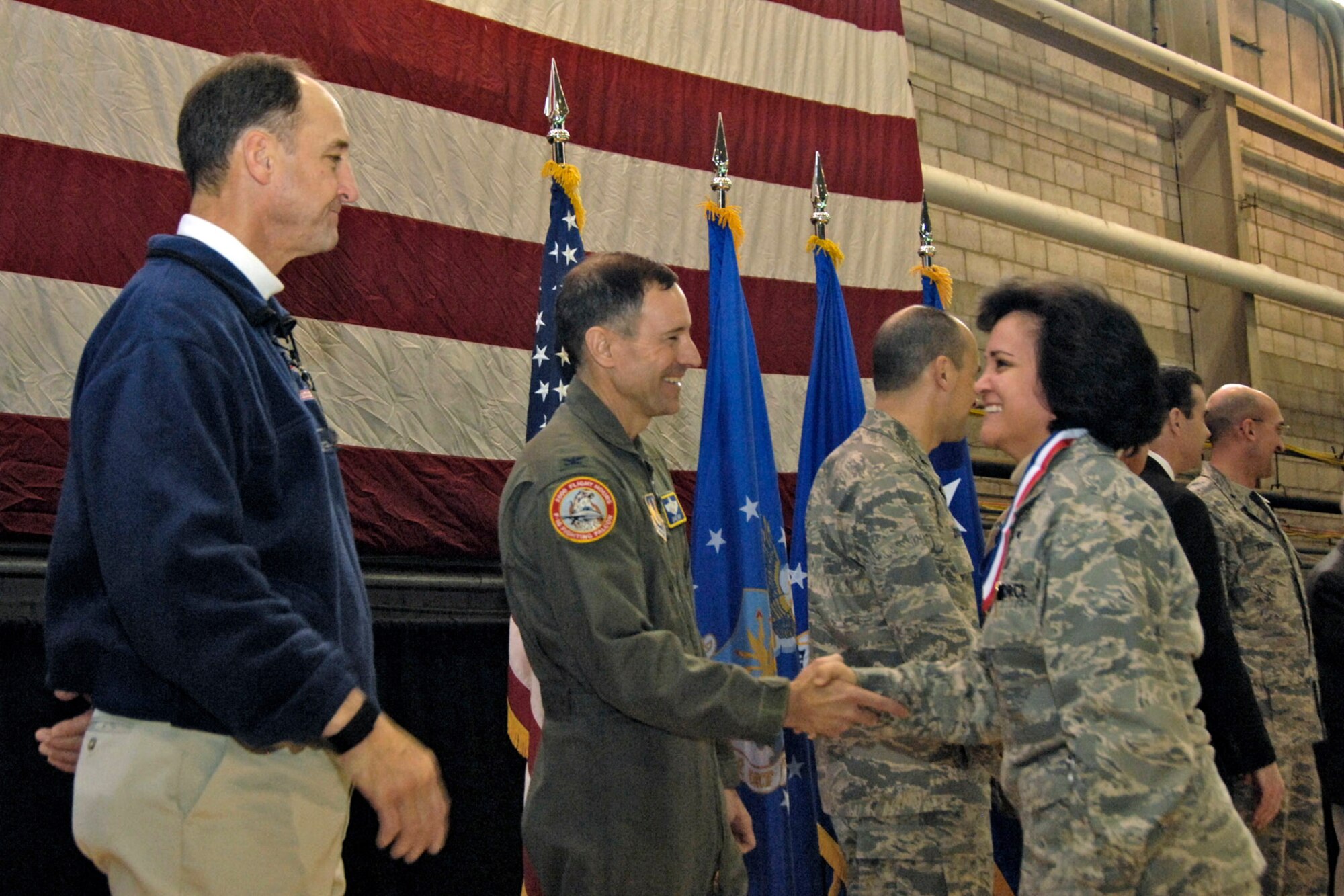 Maj. Elisa Valenzuela (right) is welcomed home by Col. David Orr (second from left)and former New England Patriots quarterback Steve Grogan (far left) during the Heroes' Homecoming celebration Dec. 12 at Hanscom Air Force Base, Mass. The event welcomed home more than 45 base Airmen who deployed during the past six months. Colonel Orr is the 66th Air Base Wing commander. (U.S. Air Force photo/Linda LaBonte Britt) 
