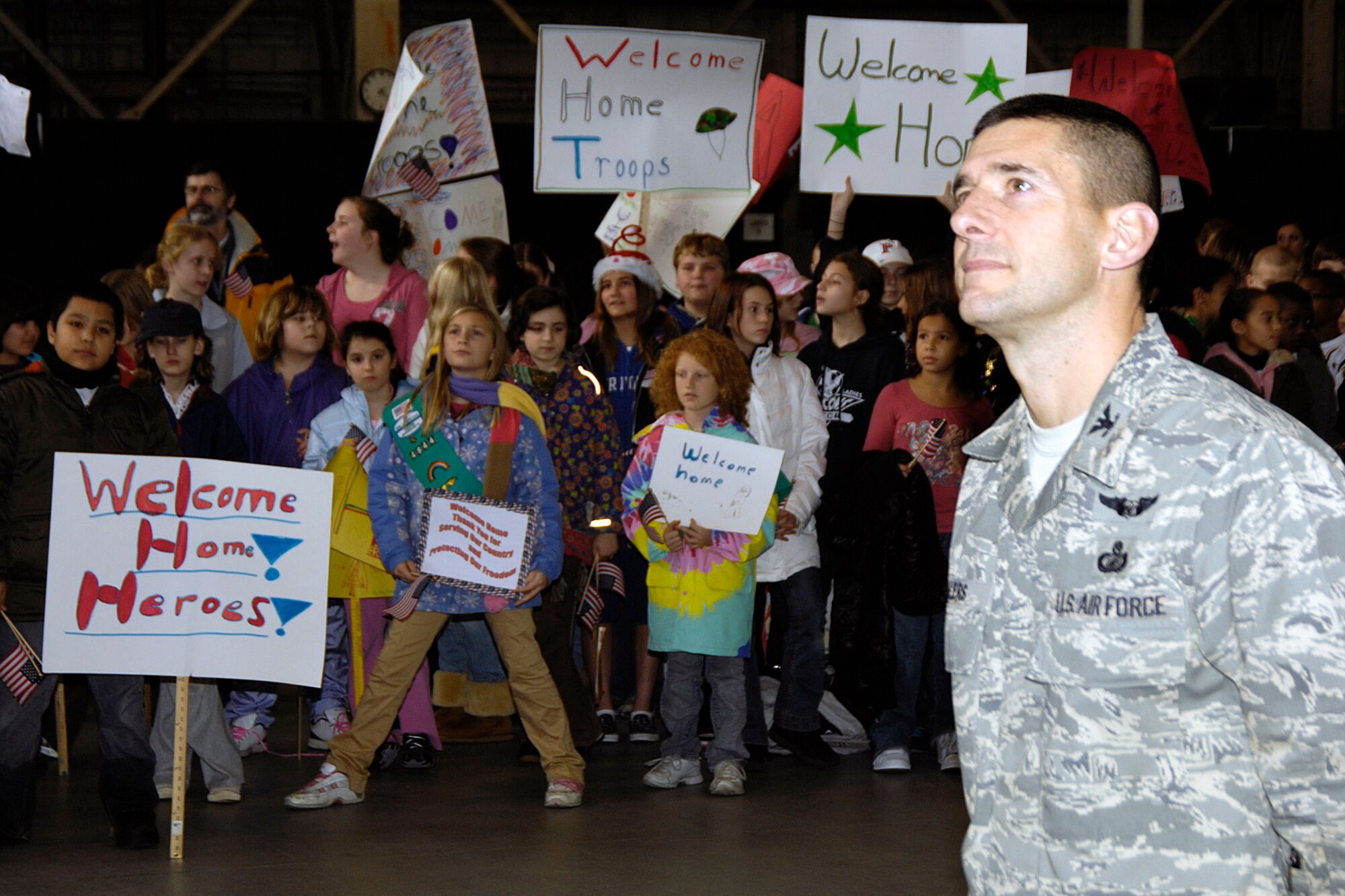 Col. Russell Fellers stands in formation while students from the Hanscom Middle School hold signs to welcome the colonel and more than 45 Airmen home from deployments during the Heroes' Homecoming celebration Dec. 12 at Hanscom Air Force Base, Mass. (U.S. Air Force photo/Linda LaBonte Britt) 
