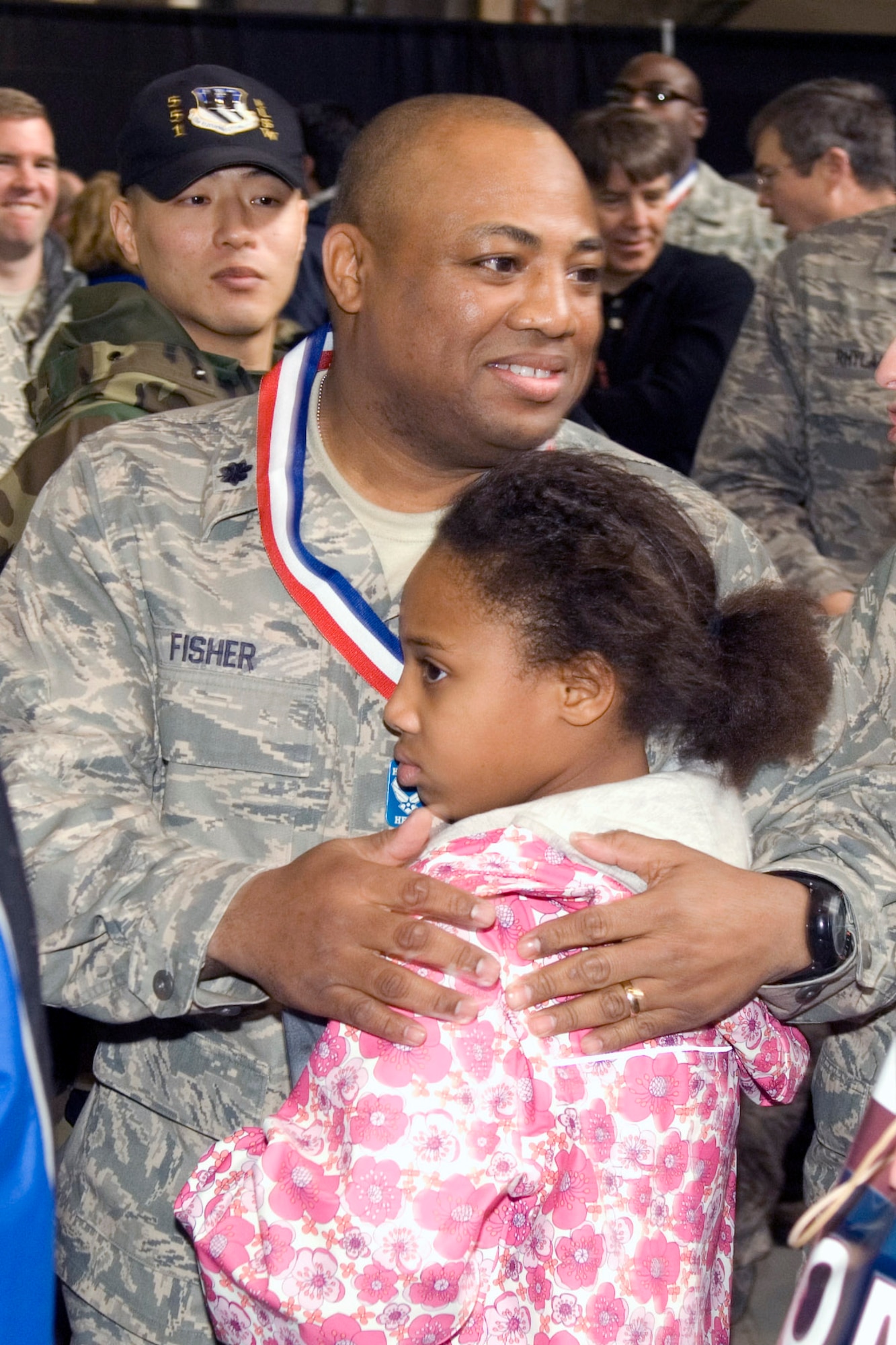 Lt. Col. Tyron Fisher hugs his daughter Tyra during the Heroes' Homecoming celebration Dec. 12 at Hanscom Air Force Base, Mass. The event officially welcomed home base Airmen who deployed over the past six months. Colonel Fisher returned from his deployment to Iraq one hour before the start of the ceremony. He is the 632nd Electronic Systems Squadron commander. (U.S. Air Force photo/Rick Berry) 
