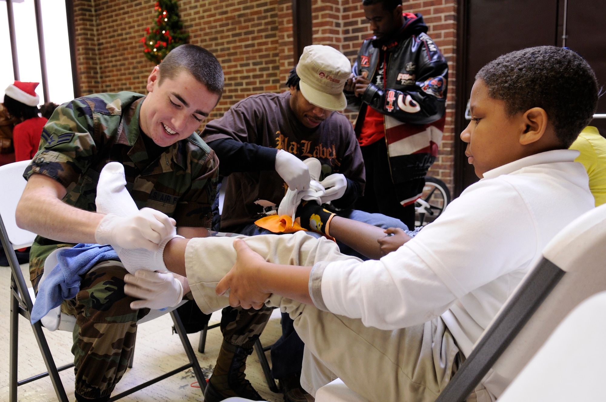 Airman 1st Class Nick Muller, 744th Communications Group, puts new socks on an elementary school student at the 7th District annual Christmas Party Dec. 12, in Washington. Eighteen Airmen from Bolling AFB and the Pentagon volunteered to put shoes on the feet of 220 children, serve food, wrap gifts and clean up. (U.S. Air Force photo by Staff Sgt. Dan DeCook)