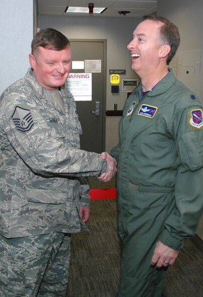 Master Sgt. Jason Winer (left) shakes the hand of Lt. Col. Marc Peterson, Peterson Installation Control Center director, after cutting the ribbon leading to the newly-combined PICC Dec. 16, 2008, at Peterson Air Force Base, Colo. The combined control center, an Air Force Smart Operations-21 initative, consolidates active duty and Air Force Reserve command post resources into one location. The streamlined efforts allow for more experienced reservists to mentor their active duty counterparts while allowing the active duty Airmen to enhance their skills with both space and aircraft-related command post duties. Sergeant Winer is a 302nd AW command post technician. (U.S. Air Force photo/Stephen J. Collier)