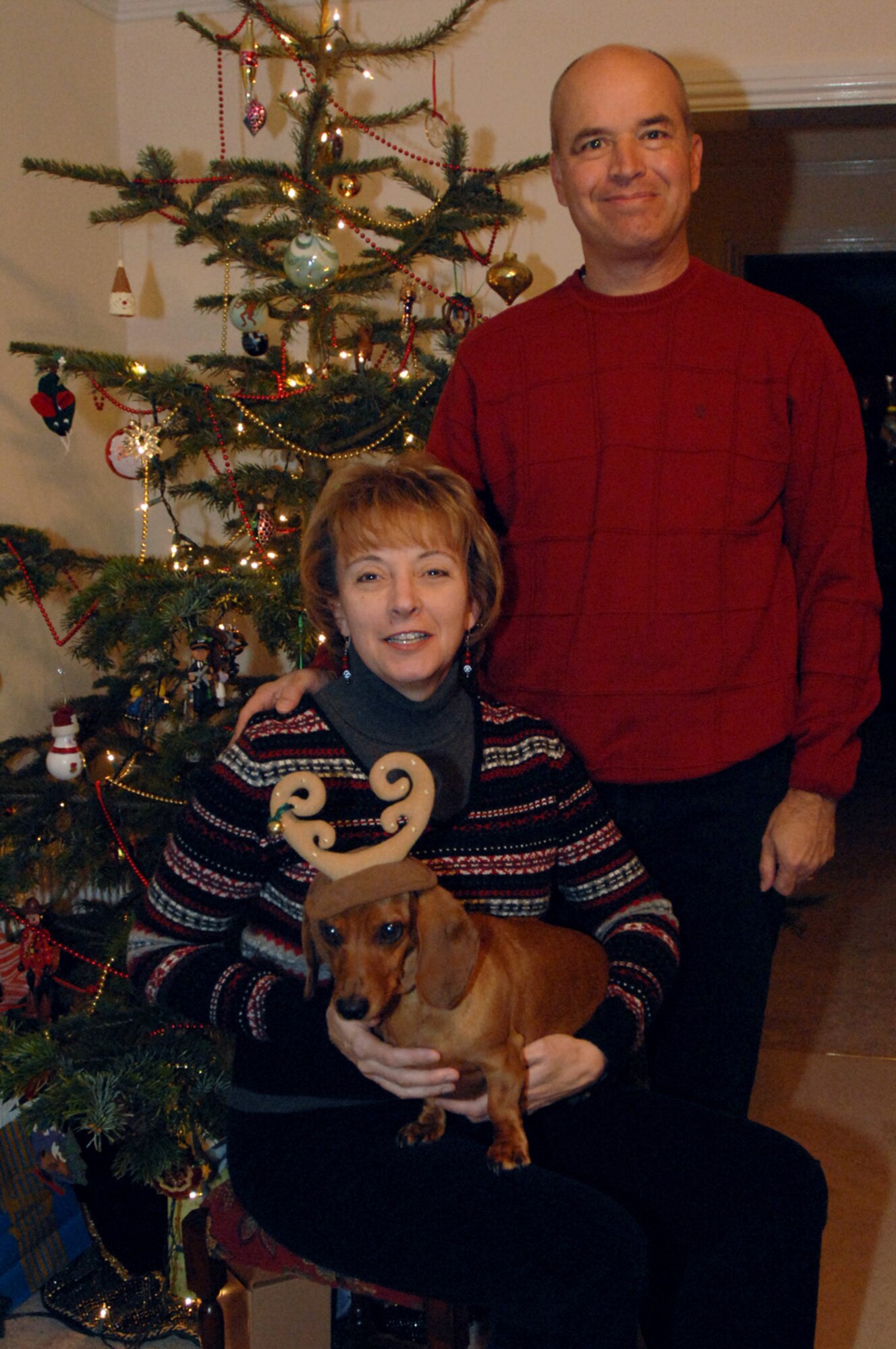 Col. Eden J. Murrie, 100th Air Refueling Wing commander, and her husband Jon wish Team Mildenhall Happy Holidays while the family dog, Ginger tries out a new holiday look. (U.S. Air Force photo by Senior Airman Teresa Hawkins)