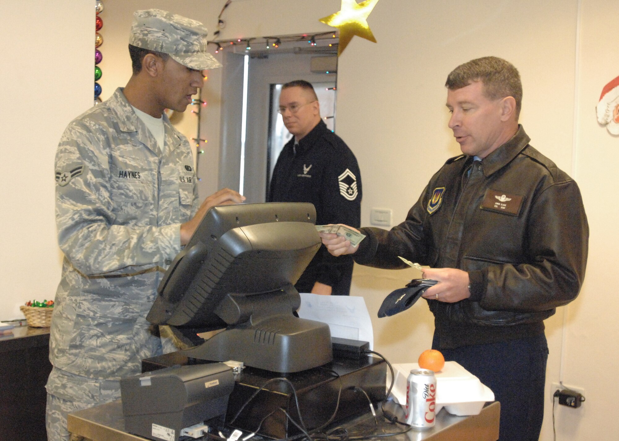 Col. David Slade, 31st Mission Support Group commander, purchases a grab-n-go meal from Airman 1st Class Shaun Haynes of the 31st Force Support Squadron during the grand opening of the La Dolce Vita Dining Facility's Grab-n-Go Flight Kitchen Dec. 15. The kitchen is geared toward serving those Airmen who don't have enough time to dine-in for a hot meal. The expanded service also allows maintainers and flight line personnel to remain in their flight line duty attire to pick-up their meals. The flight kitchen will offer grab-n-go meals from 11 a.m. to 9 p.m. and hot meals to go from 11 a.m. to 1 p.m. and 5-7 p.m. Customers can also call in or fax orders for five people or more in advance. (U.S. Air Force photo/Staff Sgt. Lindsey Maurice)