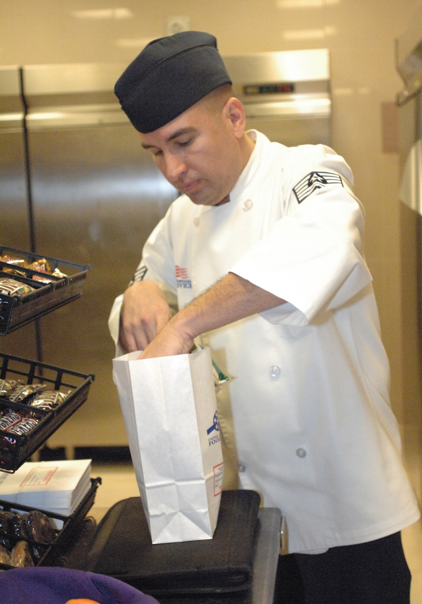 Tech Sgt. Manuel Gaytan, La Dolce Vita Dining Facility manager, packages a meal for a customer during the grand opening of the facility's Grab-n-Go Flight Kitchen Dec. 15. The kitchen is geared toward serving those Airmen who don't have enough time to dine-in for a hot meal. The expanded service also allows maintainers and flight line personnel to stay in their flight line duty attire to pick-up their meals. The flight kitchen will offer grab-n-go meals from 11 a.m. to 9 p.m. and hot meals to go from 11 a.m. to 1 p.m. and 5-7 p.m. Customers can also call in or fax orders for five people or more in advance. (U.S. Air Force photo/Staff Sgt. Lindsey Maurice)