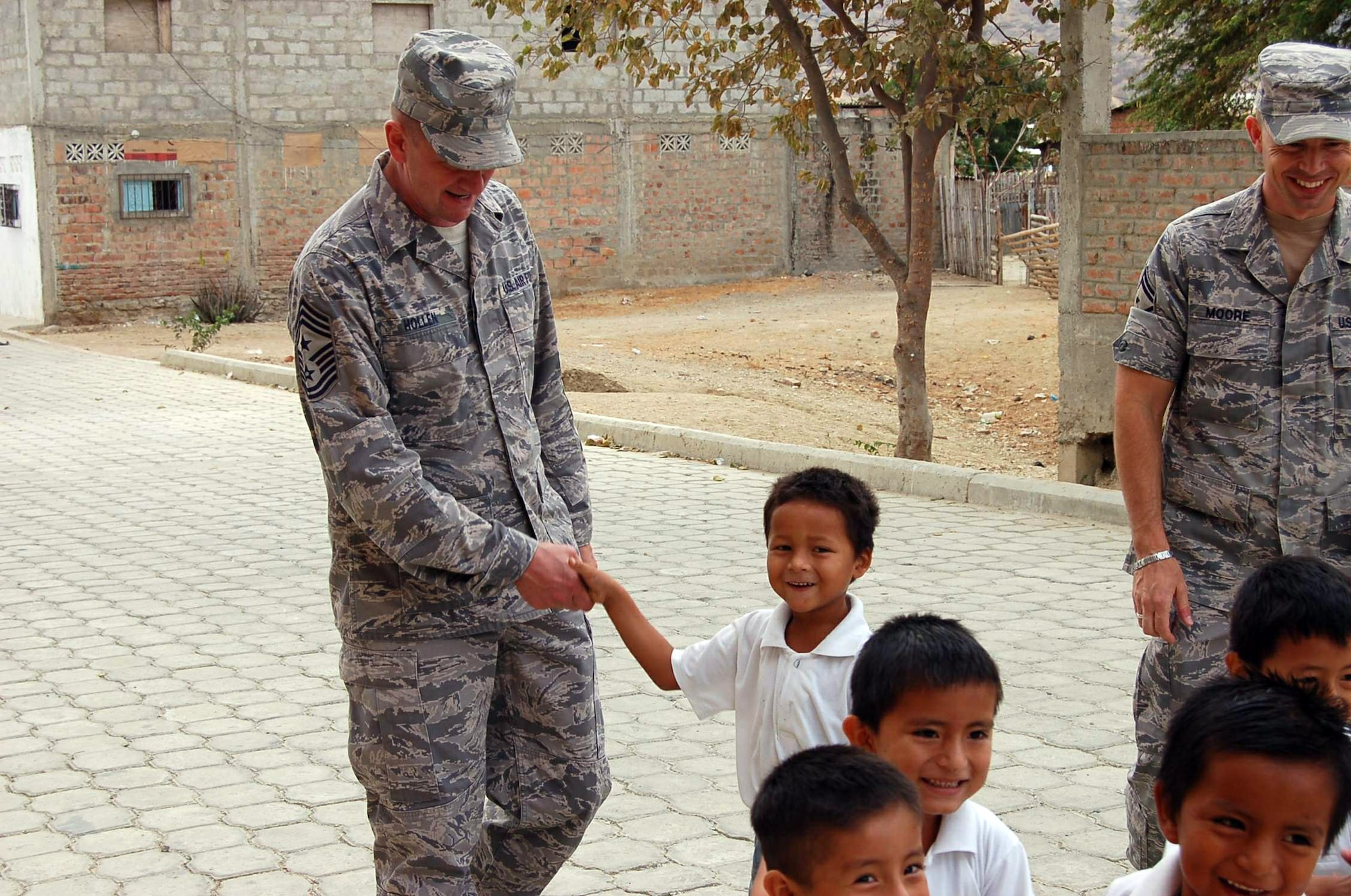 Chief Master Sgt. Lloyd Hollen greets a student before walking to the school's center to watch the presentation of Southern Command's Humanitarian Assistance Program donation of school supplies Dec. 10 in San Juan, Ecuador. Chief Hollen is the command chief for the Air Forces Southern and 12th Air Force. (U.S. Air Force photo/Tech. Sgt. Matthew McGovern) 
