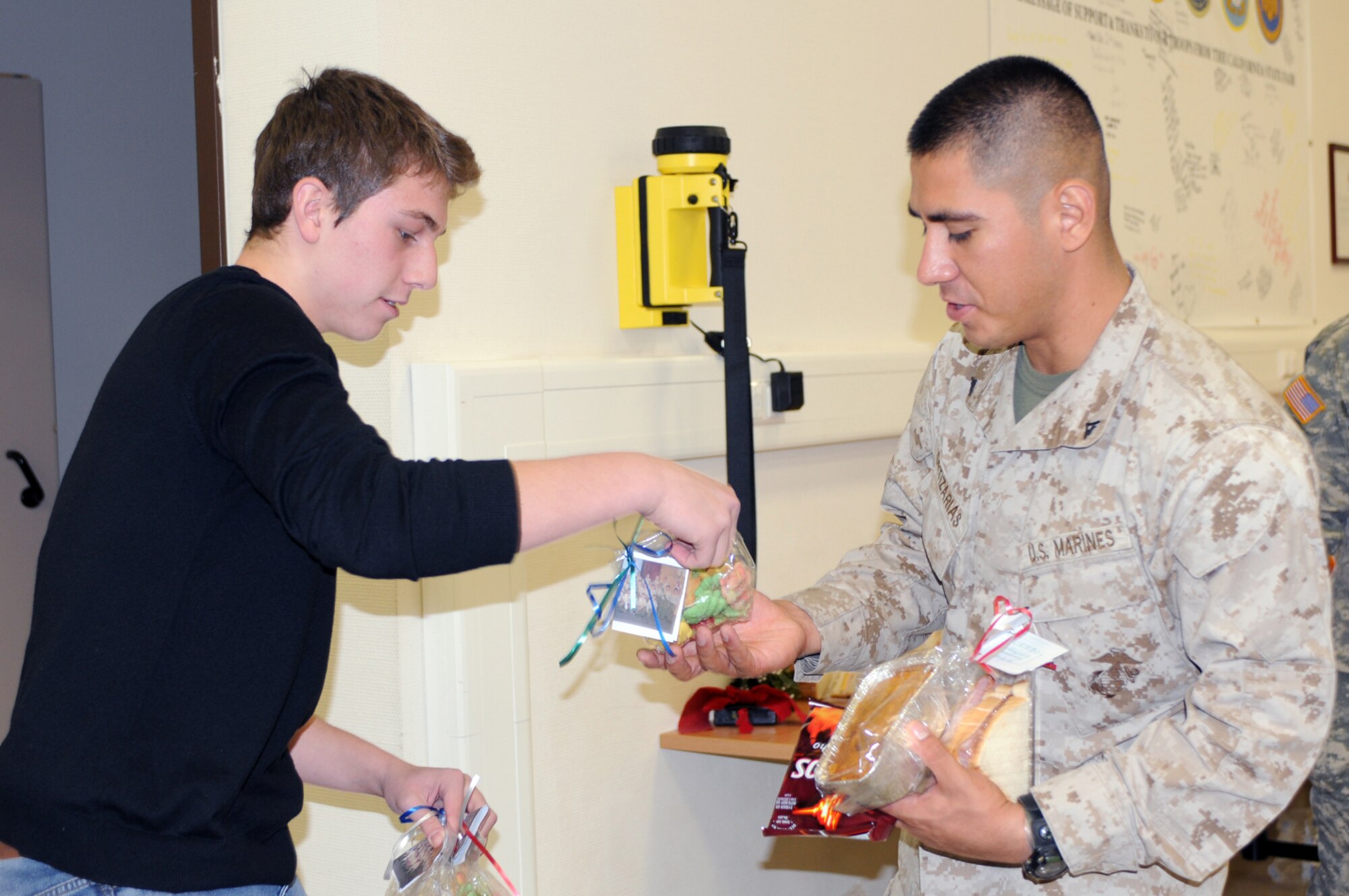 Ian DiFiore, a Boy Scout from NJ, hands out cookies to a Marine transitioning back to the states at the Contingency Aero-medical Staging Facility as part of his Eagle Scout service project, Ramstein Air Base, Germany Dec. 12. With the help of 35 scouts, over 175 hours have gone into his service project. (U.S. Air Force photo by Senior Airman Kelly LeGuillon)