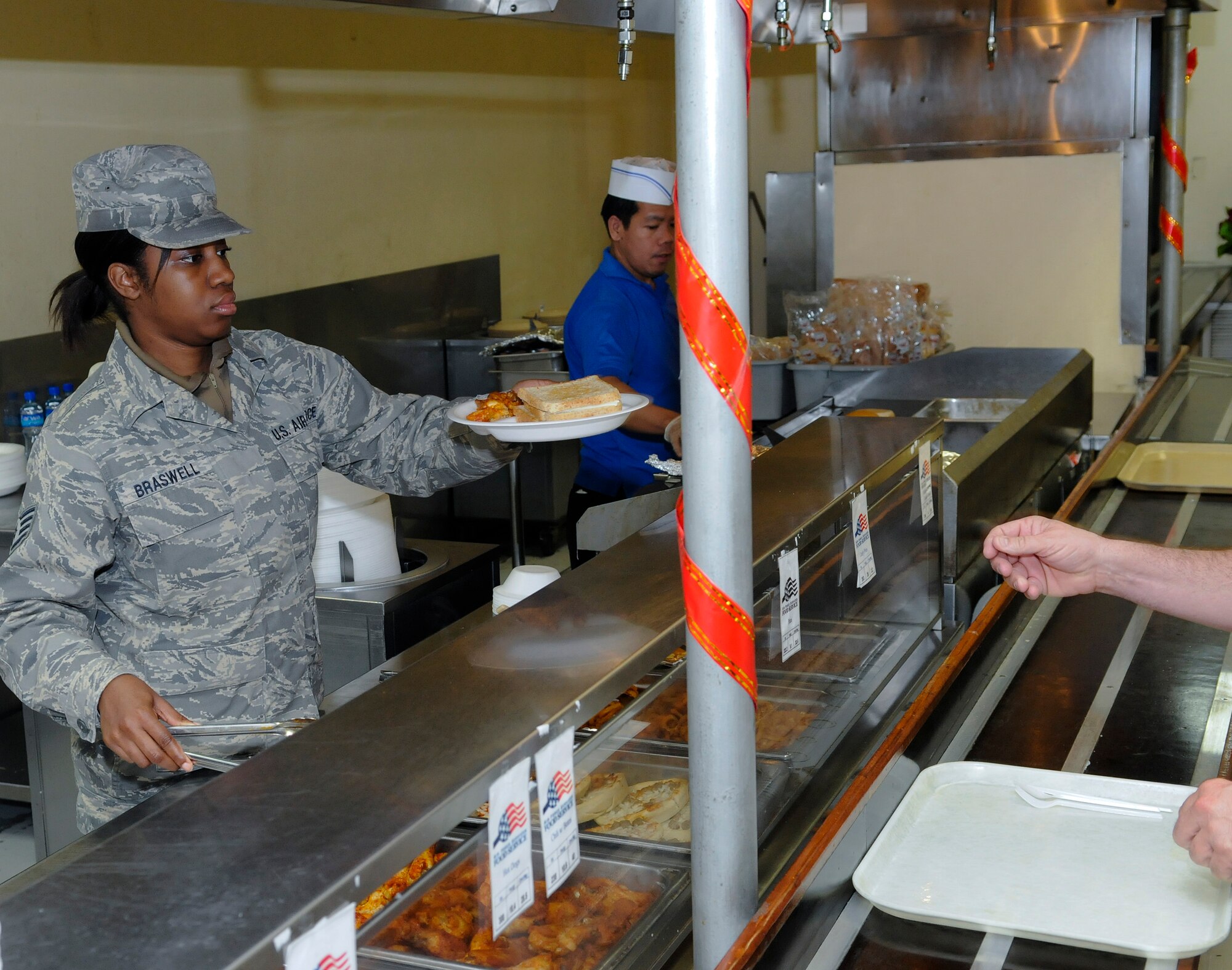 Staff Sgt. Brandi Braswell, a food service quality assurance technician assigned to the 379th Expeditionary Force Support Squadron, helps serve food at the Manhattan Dining Facility, Dec. 15, at an undisclosed air base in Southwest Asia.  The 379 EFSS Food Service Flight operates four dining facilities that support over 2 million patrons every AEF rotation.  It is the largest Air Force food service operation in the Central Command area of responsibility and the second largest in the Air Force.  Sergeant Braswell, a native of Macon, Ga., is deployed from Robins Air Force Base, Ga., in support of Operations Iraqi and Enduring Freedom and Joint Task Force-Horn of Africa.  (U.S. Air Force photo by Tech. Sgt. Michael Boquette/Released)