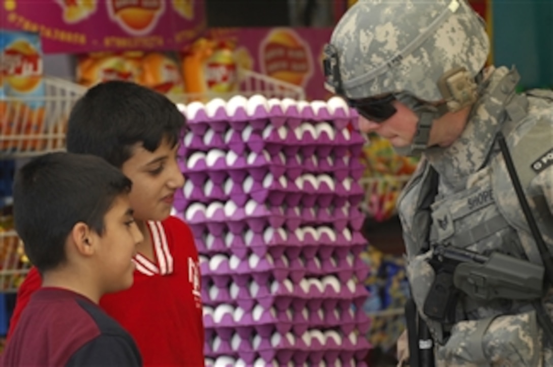 U.S. Air Force Staff Sgt. Kane Shope speaks with Iraqi children in a market during a walking patrol in the Rashid community of southern Baghdad, Iraq, on Dec. 4, 2008.  Shope is assigned to Detachment 3, 732nd Expeditionary Security Forces Squadron attached to 1st Brigade Combat Team, 4th Infantry Division.  