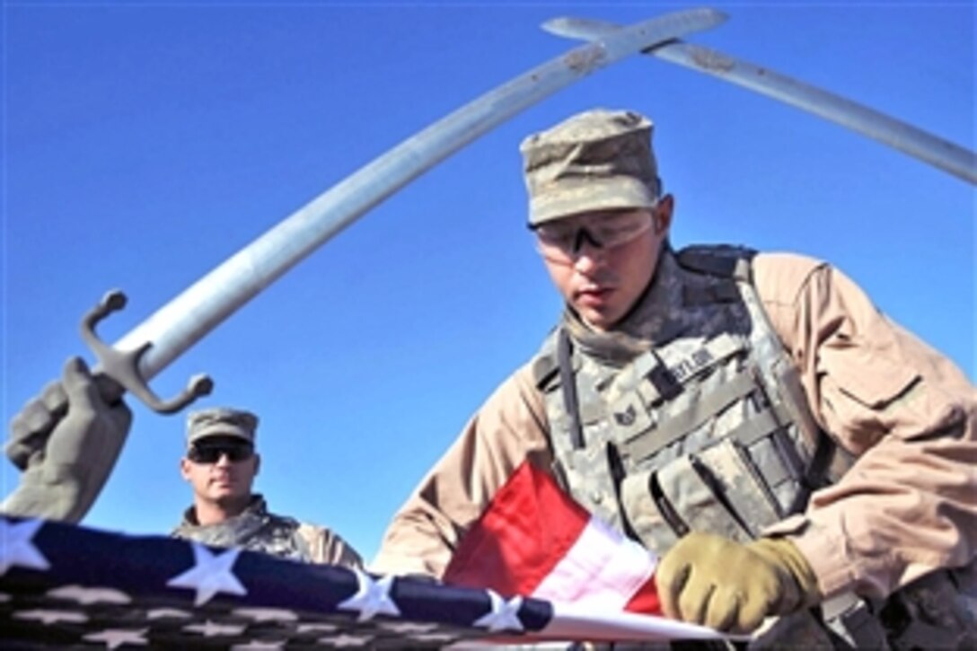 U.S. Air Force Staff Sgt. Daniel Taylor folds an American flag after a photo opportunity in front of the Crossed Swords in Baghdad, Iraq, Dec. 4, 2008. Taylor is assigned to the 4th Infantry Division's 11th Security Forces Squadron, Detachment 3, 732nd Expeditionary Security Forces Squadron, 1st Brigade Combat Team.