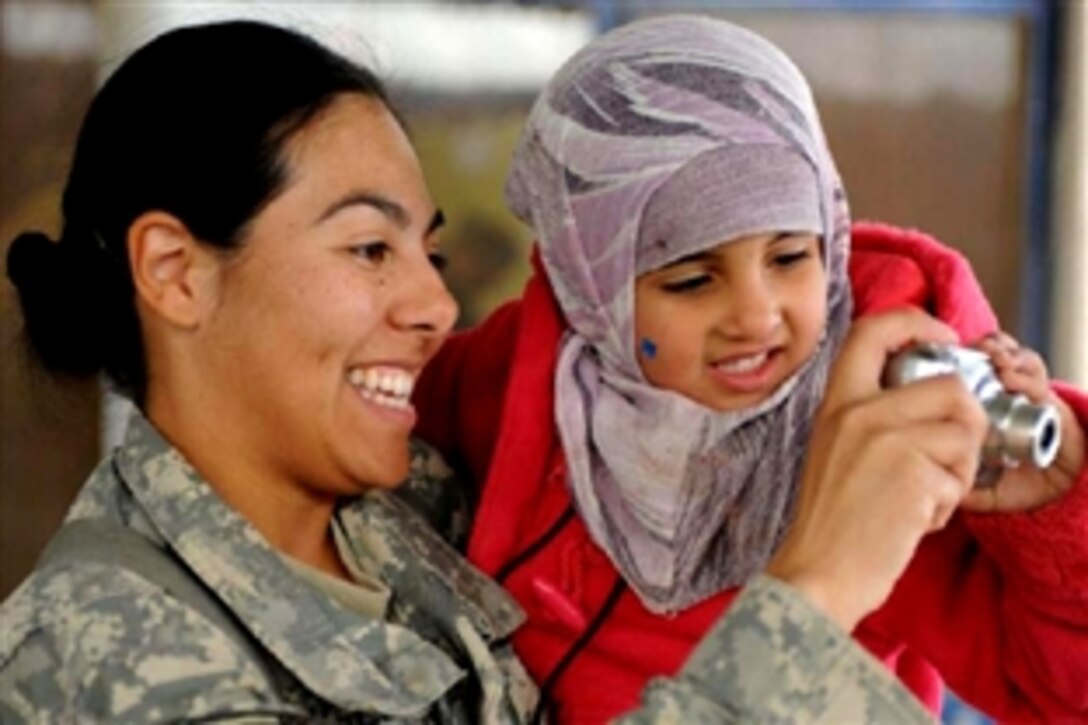 U.S. Army Staff Sgt. Angelina Mureno plays with a young Iraqi girl from the school for special needs children in Rumaythuh, Iraq, Dec. 11, 2008. The students are visiting Combat Operations Base Adder to have the girl's hearing tested. If she qualifies, she will be given a hearing aid. Mureno is assigned to the 4th Brigade, 1st Cavalry Division. 