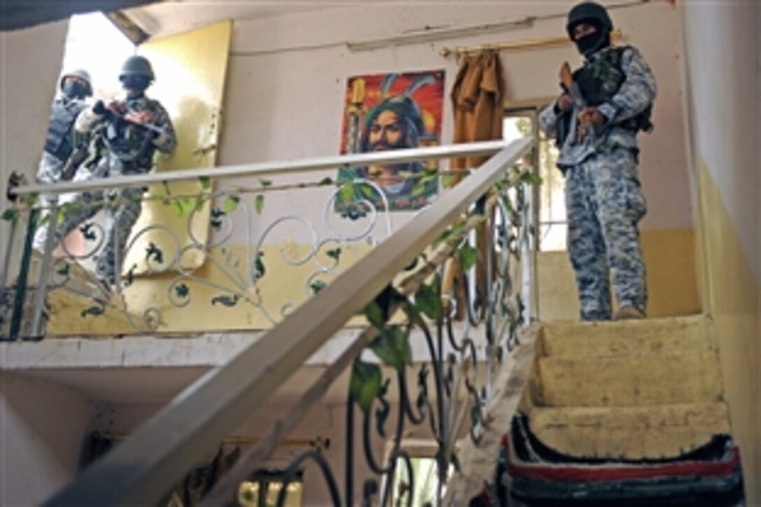Iraqi police secure the premises while fellow officers search the house of a suspected criminal during a cordon and search operation in Diwaniyah, Iraq, Dec. 10, 2008. The Iraqi police and Iraqi army worked together to complete the operation.