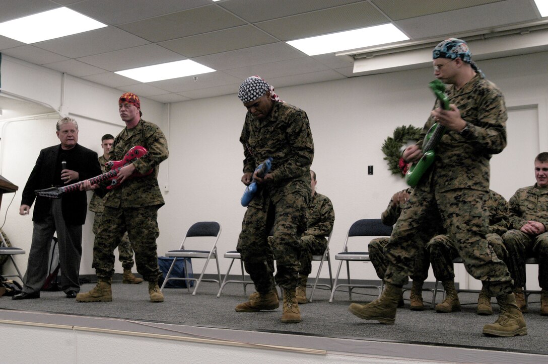 CAMP H.M. SMITH, Hawaii -- Comedian Ken Whitener looks on as Sgt. Robert Manion, MarForPac chemical, biological, radiological and nuclear NCO, Sgt. Aaron D. Holt, MarForPac telephone NCO, and Chief Warrant Officer 4 Chris Doman, MarForPac financial management resource officer, rock out during the 2008 Holiday Fun Safety Stand Down Dec. 17. Whitener engaged the audience by using his comedy and hypnosis routines to encourage Marines to make the right choices over the holidays.