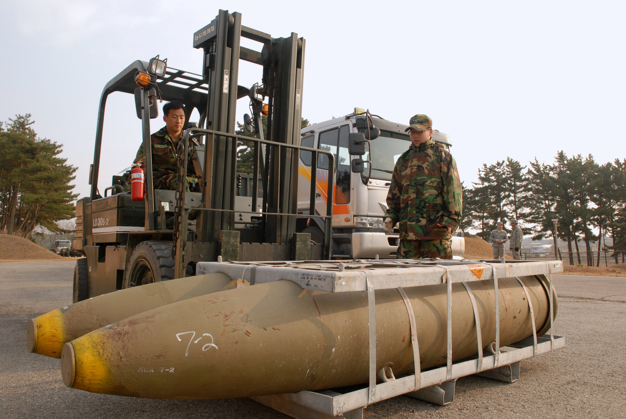 KUNSAN AIR BASE, Republic of Korea -- Republic of Korea Air Force Airman 1st Class Jin Seok Kim picks up MK-84 general purpose bombs with a fork lift while Staff Sgt. Jong Mun Park directs the operation, here Dec. 17. (U.S. Air Force photo by: Senior Airman Angela Ruiz)(