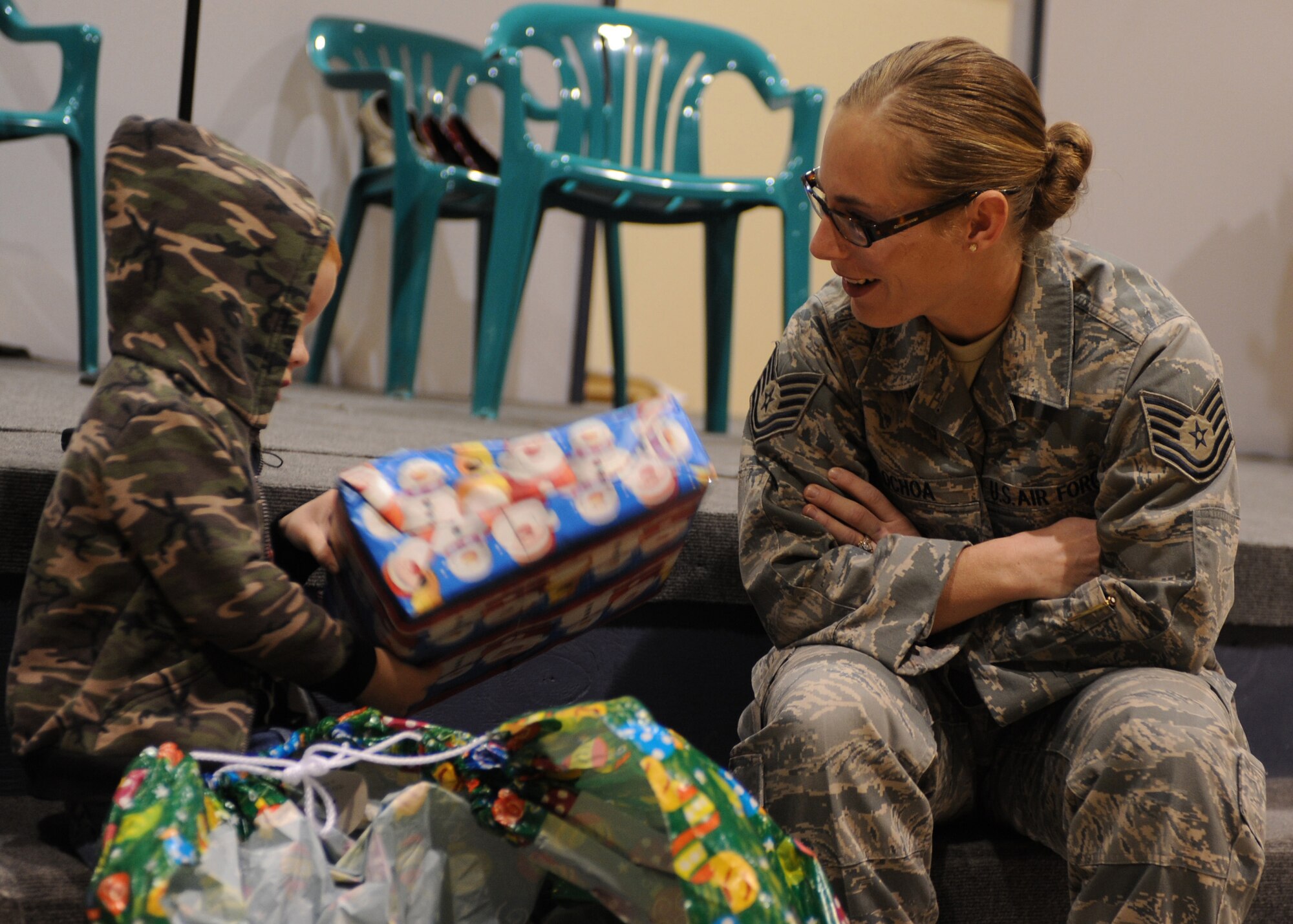 CANNON AIR FORCE BASE, N.M. -- Tech. Sgt. Jennifer Ochoa, 27th Special Operations Logistics Readiness Squadron, helps a child unwrap gifts during the Angels in Blue gift-giving event, Dec. 13. Angels in Blue is a base-wide program through which Cannon personnel sponsor a local child and buy him or her gift during the holiday season. (U.S. Air Force photo/Airman 1st Class Evelyn Chavez) 