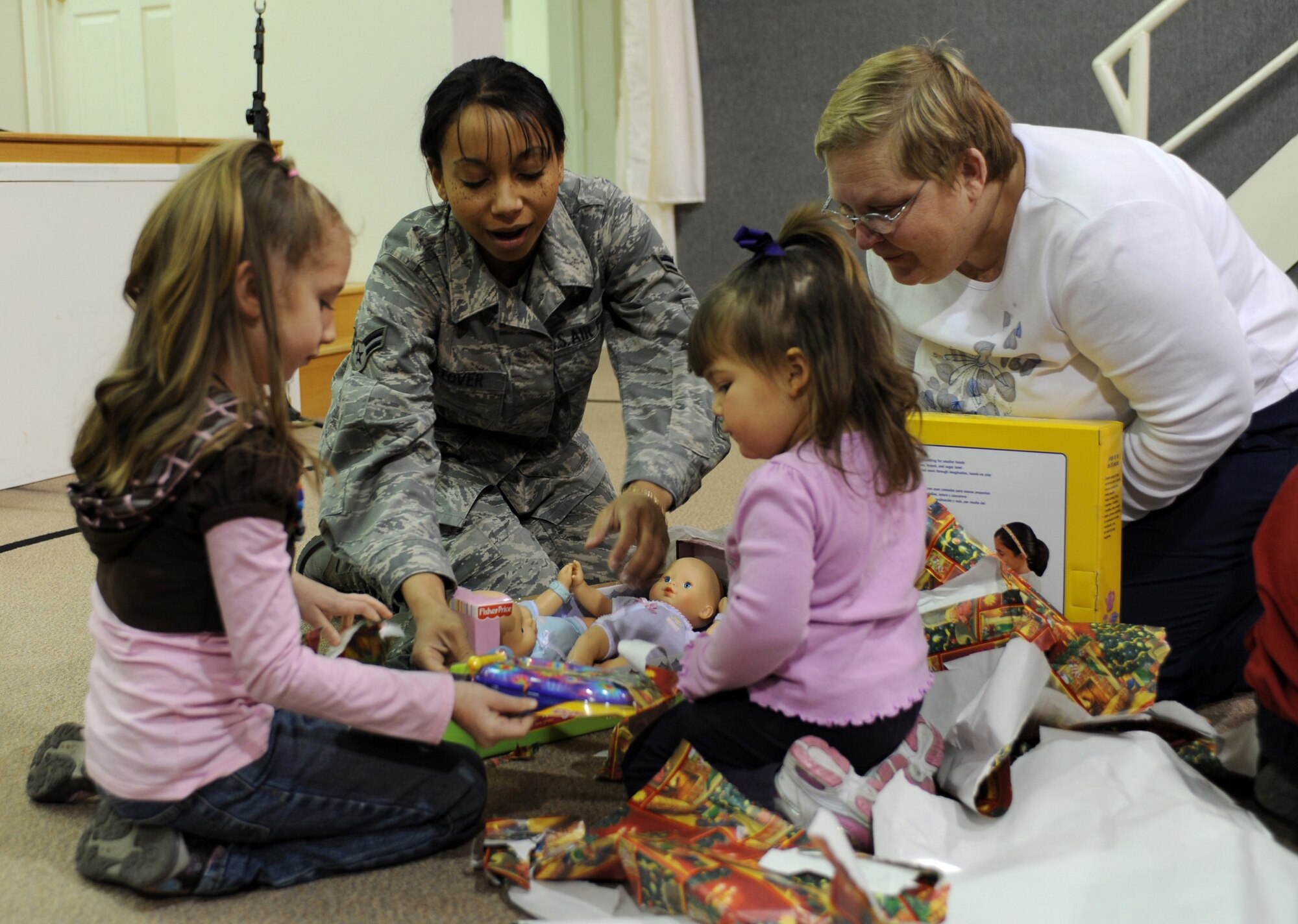 CANNON AIR FORCE BASE, N.M. - Airman 1st Class D'Andrea Stover, 27th Special Operations Medical Support Squadron, helps children unwrap gifts Dec. 6 during this year's Angels in Blue gift-giving party. Angels in Blue is a base-wide program through which Cannon personnel sponsor a local child and buy him or her gift during the holiday season. (U.S. Air Force photo/Airman 1st Class Evelyn Chavez)