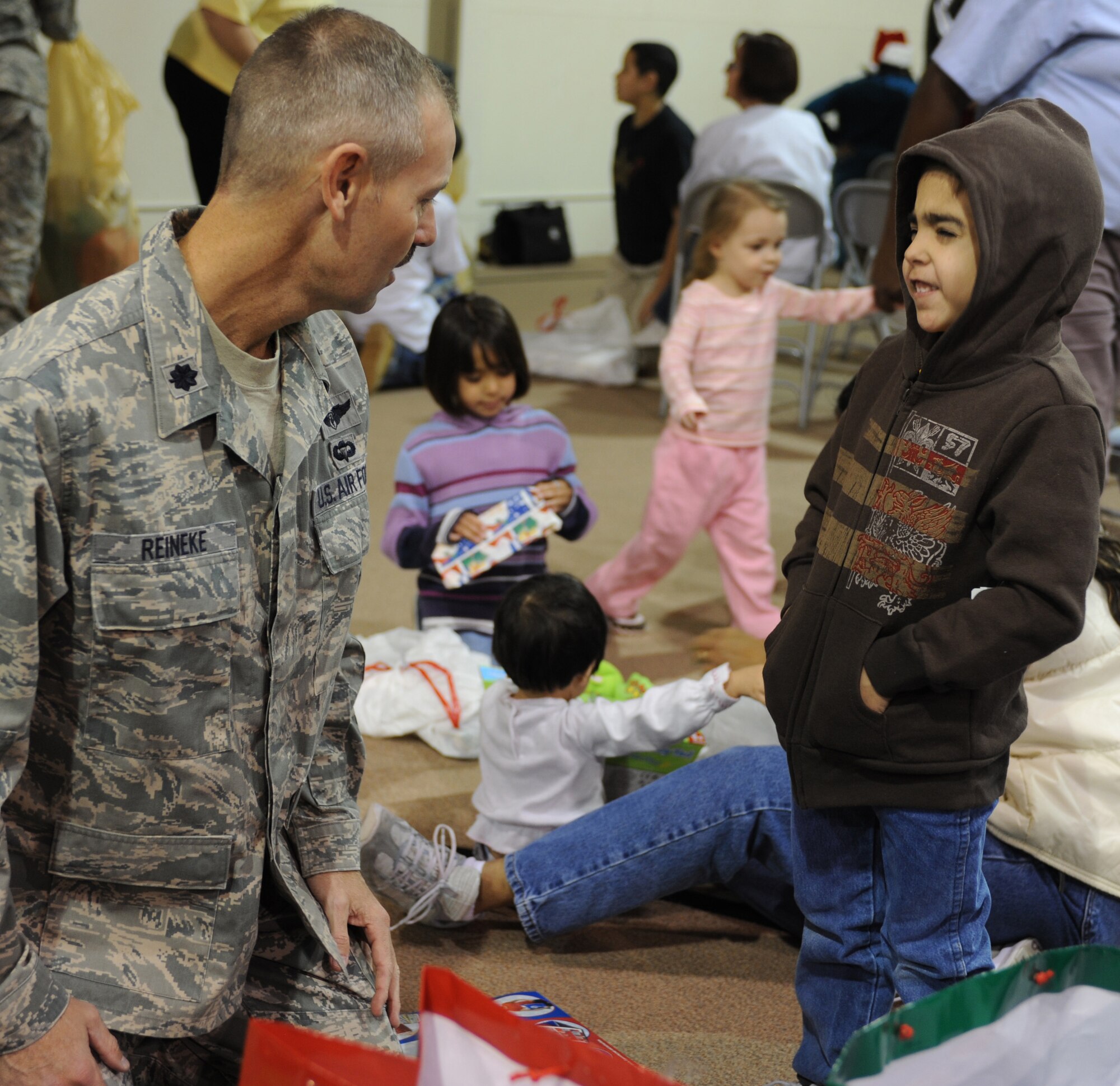 CANNON AIR FORCE BASE, N.M. - Lt Col. James Reineke, 27th Special Operations Medical Operations Squadron commander, helps Trevor Daniell, a child at the New Mexico Christian Children's Home, unwrap Christmas gifts during this year's Angels in Blue gift-giving party. Angels in Blue is a base-wide program through which Cannon personnel sponsor a local child and buy him or her gift during the holiday season. (U.S. Air Force photo/Airman 1st Class Evelyn Chavez)