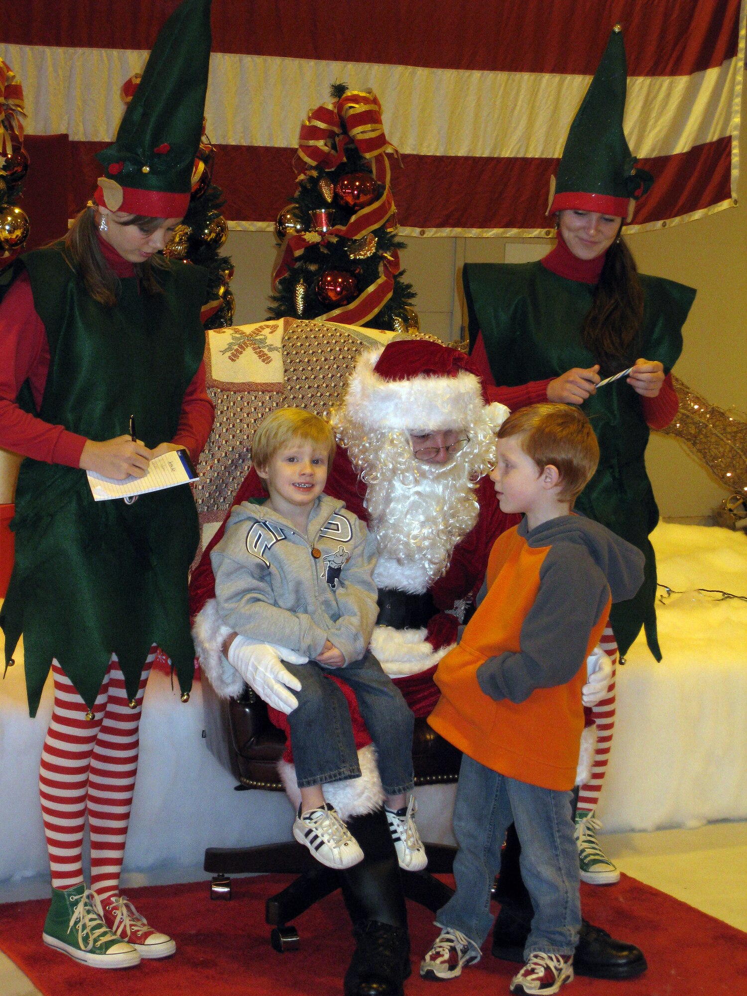 Cayden Anderson, left, and his brother, Baylar, enjoy talking with Santa Claus and his elves at Breakfast with Santa on Dec. 13, in Hangar 170 on base.  (Photo by Sarah Putnam)