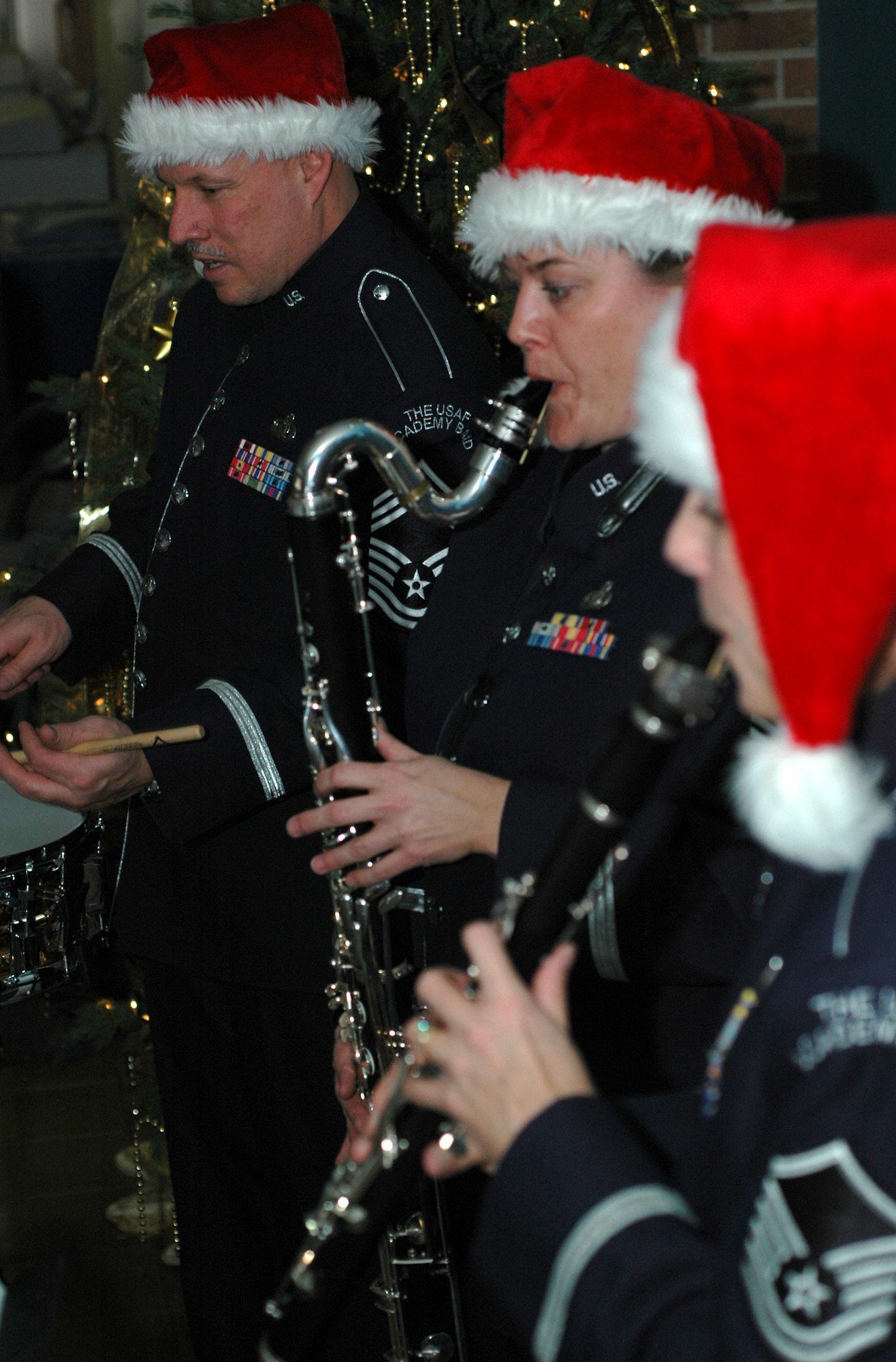 (Right to left): Master Sgts. Noelle Little and Claudia Weir as well as Chief Master Sgt. Scott Barbier bring out the yule tide glee of 302nd Airlift Wing members Dec. 17, 2008, with a musical ensemble in the wing's headquarters building on Peterson Air Force Base in Colorado. Each members of the U.S. Air Force Academy band, they played throughout the base to sharpen their skills as well as provide additional morale and espirit de corps to its ranks. Sergeant Little plays the clarinet, Sergeant Weir makes use of the bass clarinet and Chief Barbier bangs on the percussion drum. (U.S. Air Force photo/Stephen J. Collier)