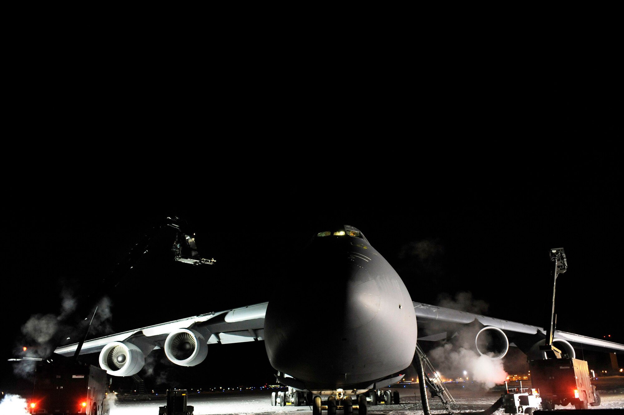 Two de-icer vehicles work on a C-5M Super Galaxy after the aircraft sat outside for more than 24 hours in temperatures as low as minus 25 degrees during a cold weather test Dec. 14 at Eielson Air Force Base, Alaska. This is the first upgraded C-5M to go through cold-weather testing. (U.S. Air Force photo/Senior Airman Jonathan Snyder) 
