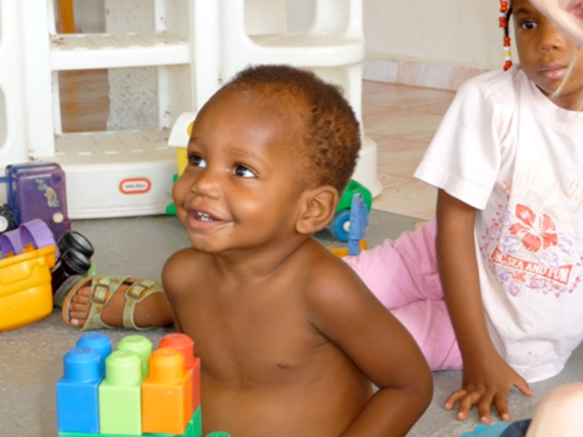 A child at the Siloam Children's Hospice in Curacao, Netherland Antilles, smiles at Airmen during playtime with volunteers Friday, Dec. 12th.  The home for orphaned, abandoned, abused and terminally ill children has captured the hearts of 429th Expeditionary Operations Squadron Airmen as they regularly volunteer to maintain the compound's grounds, paint, donate toys and their free time to provide a safe and comfortable environment for residents. (Photo by: Capt. Nathan Broshear, Twelfth Air Force (AFSOUTH) Public Affairs)
