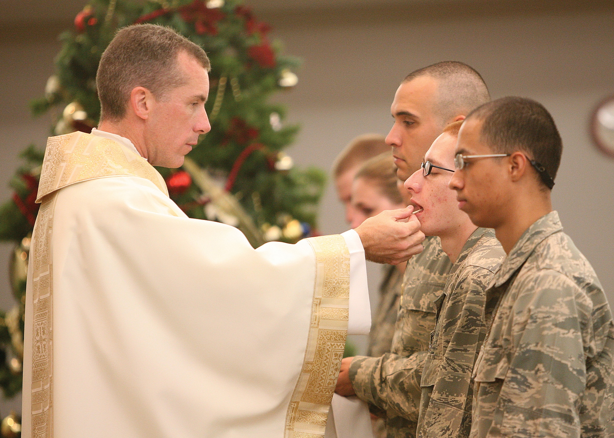 Basic trainees receive communion from Chaplain (Lt. Col.) Michael Butler during mass Dec. 8 at Lackland Air Force Base, Texas. Chaplain Butler recently was bestowed the honor of monsignor in the Roman Catholic Church. (U.S. Air Force photo/Robbin Cresswell) 
