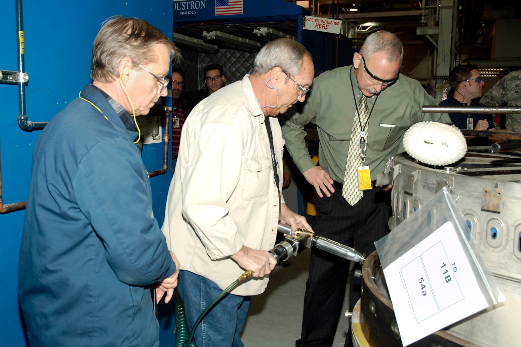 From left, design engineer, Tom Pence and drill operator, Jerry Heiskill, show Oklahoma City Air Logistics Center Executive Director John Over the improved process for drilling a duct-liner. The two men are part of a team that combined a process improvement and safety improvement to save the Air Force time and money. (Air Force photo)