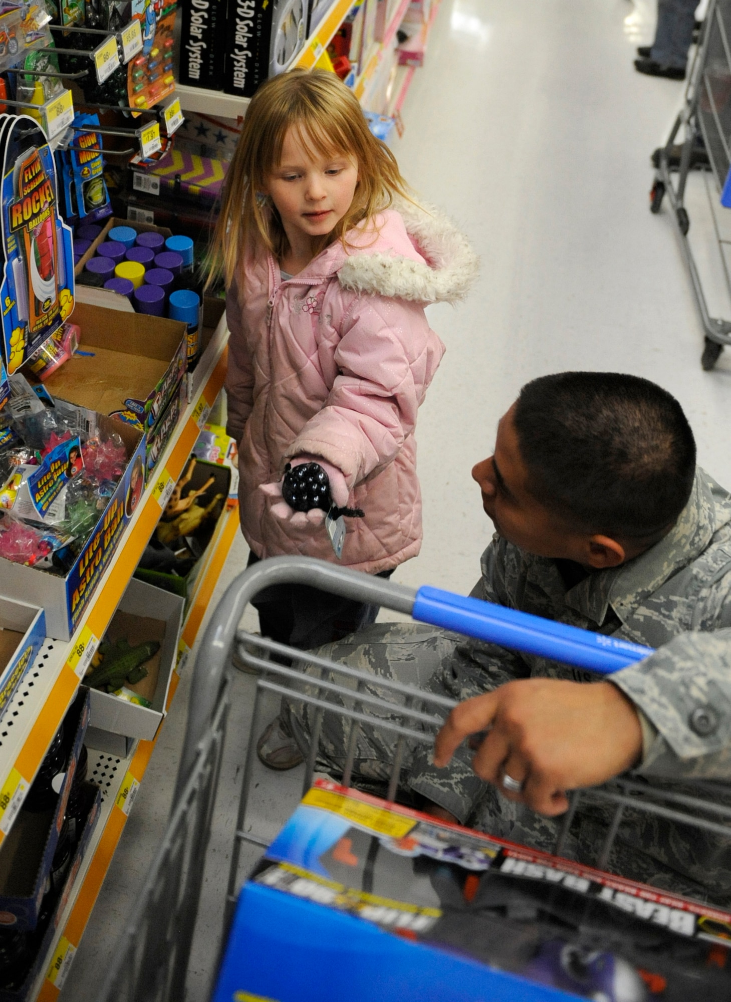 MOUNTAIN HOME AIR FORCE BASE, Idaho-- Senior Airman Andrew Hallon, 366th Security Forces Squadron, helps a  girl pick out a gift during the Mountain Home annual Shop with a Cop day held at the Wal-Mart in Mountain Home Dec. 3. Each year, the Mountain Home Police Department and the community of Mountain Home sponsor the annual Shop with a Cop day. More than 20 366th SFS people participated in this year's event. More than 110 local needy children between the ages of 5 and 12 participated this year with more than $10,000 donated by local businesses. (U.S. Air Force photo/Airman 1st Class Stephany Miller)