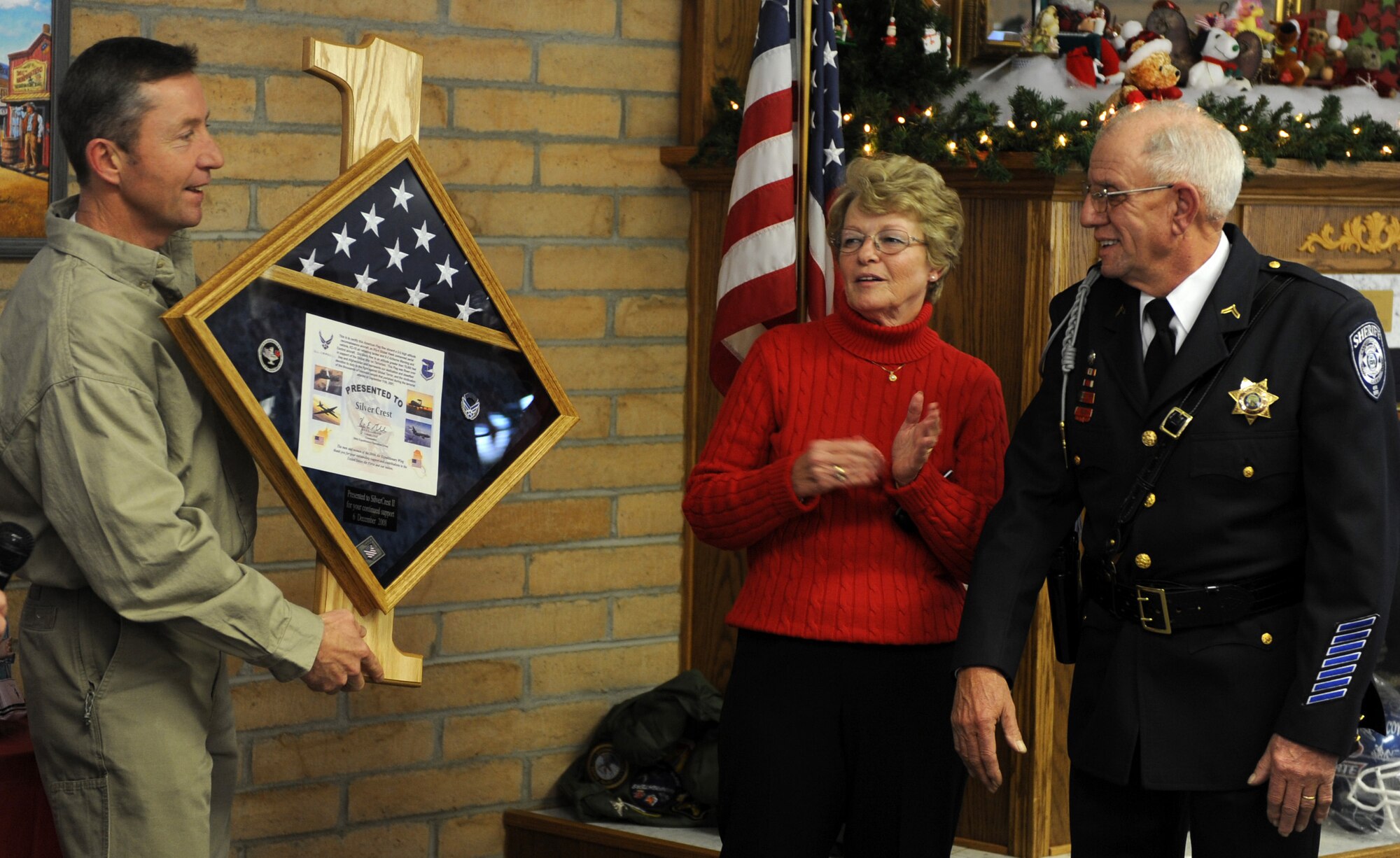 MOUNTAIN HOME AIR FORCE BASE, Idaho - Master Sgt. Jeffrey Waters, 366th Equipment Maintenance Squadron first sergeant, presents Joe Whilden and his wife, Silvercrest housing developement managers, a first sergeants plaque as a thank you during a ceremony honoring Operation Warmheart in the Silvercrest community of Nampa, Idaho, Dec. 6. The ceremony served as a way for the residents of Silvercrest to show their appreciation for Operation Warmheart, a non-profit organization that provides temporary assistance to military personnel and certain individuals and agencies from the local community. (U.S. Air Force photo/Airman Debbie Lockhart)
