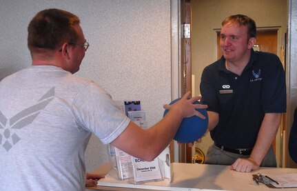 Airman 1st Class Kenneth Hales checks out a wallyball to Senior Airman David Smith at the Fitness and Sports Center on base Dec. 16. More than 250 military members, civilians and family members use the amenities daily at the gym which is open seven days a week. Airman Hales is with the 437th Force Support Squadron and Airman Smith is with the 437th Aerial Port Squadron. (U.S. Air Force photo/Airman 1st Class Melissa White)