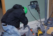 MINOT AIR FORCE BASE, N.D. -- A construction worker drills a hole through a floor in the 5th Bomb Wing headquarters building here Dec. 15. while installing a geothermal heat system. The 5th Bomb Wing headquarters building is currently undergoing construction to utilize geothermal heating by having 39 ground source heat pumps installed in the building along with 30 geothermal wells on the west side of the building. (U.S. Air Force photo by Staff Sgt. Keith Ballard)
