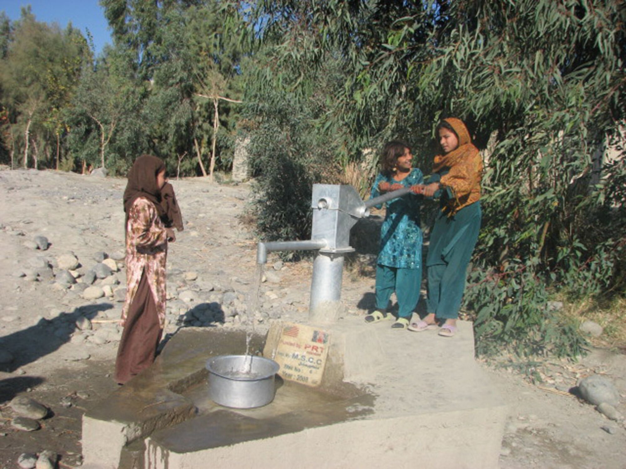 Afghan girls draw water from a recently completed village well in Kuz Konar District.  The Nangarhar PRT recently sponsored the completion of eight wells in six districts that will bring a vital water source to thousands of people in the districts. (Courtesy photo)
