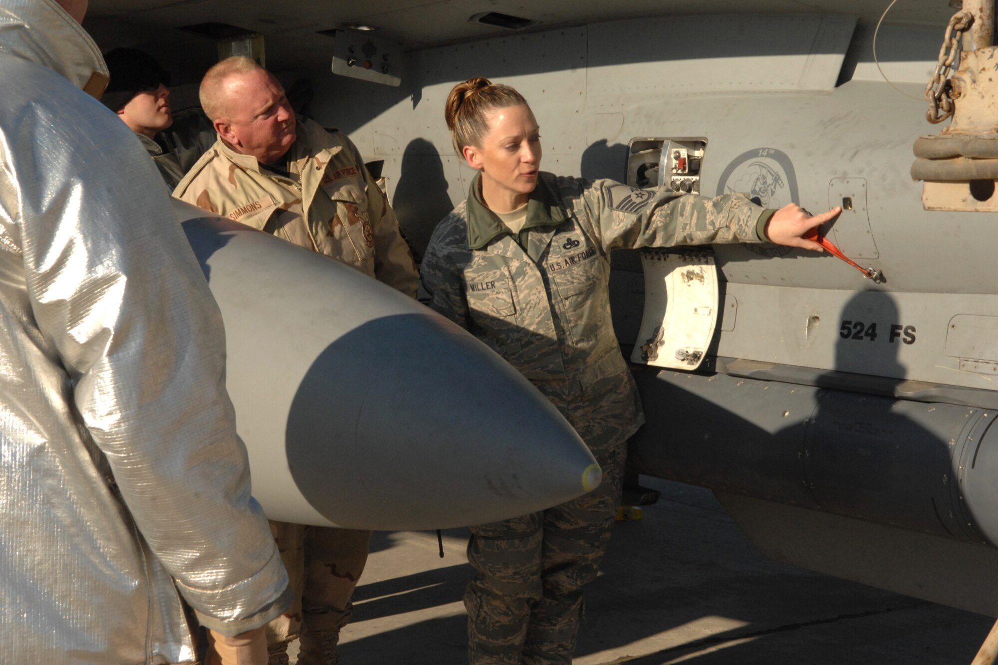 Master Sergeant Renee Miller explains the emergency power unit pin and fire indicator on an F-16 to firefighters during egress training at Kirkuk Regional Air Base, Iraq, Dec. 16. The training provided the firefighters hands-on familiarization with the jet in case of an emergency requiring egress.  The firefighters are part of the 506th Expeditionary Civil Engineering Squadron.  Sergeant Miller is the transient alert flight chief with the 506th Expeditionary Operations Support Squadron and is deployed from Luke Air Force Base, Ariz. (U.S. Air Force photo/Senior Airman Randi Flaugh)