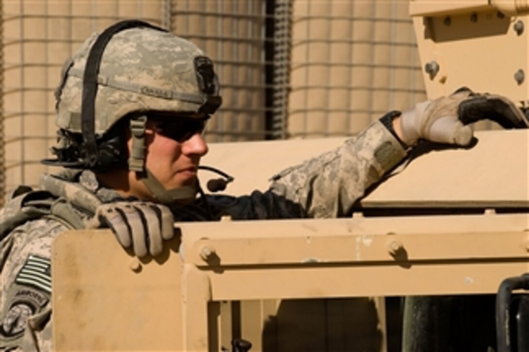 U.S. Army Spc. Kevin Lanasa, Headquarters Platoon, 21st Military Police Company, talks to his vehicle commander during a convoy stop in Basra, Iraq, on Dec. 13, 2008.  