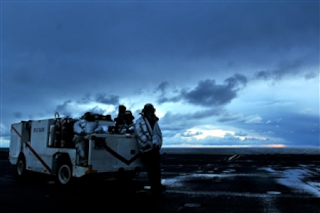 Crash and salvage personnel brace against the cold at dawn on the flight deck of the aircraft carrier USS Abraham Lincoln in the Pacific Ocean, Dec. 15, 2008. 