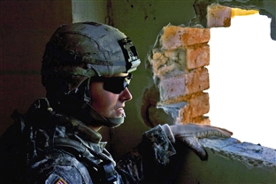 U.S. Army Sgt. Josh Roberts looks through a hole in a wall at the Algehad police station in the Algehad district of Basra, Iraq, Dec. 13, 2008. Roberts and fellow soldiers are assigned to Headquarters Platoon, 21st Military Police, Airborne.