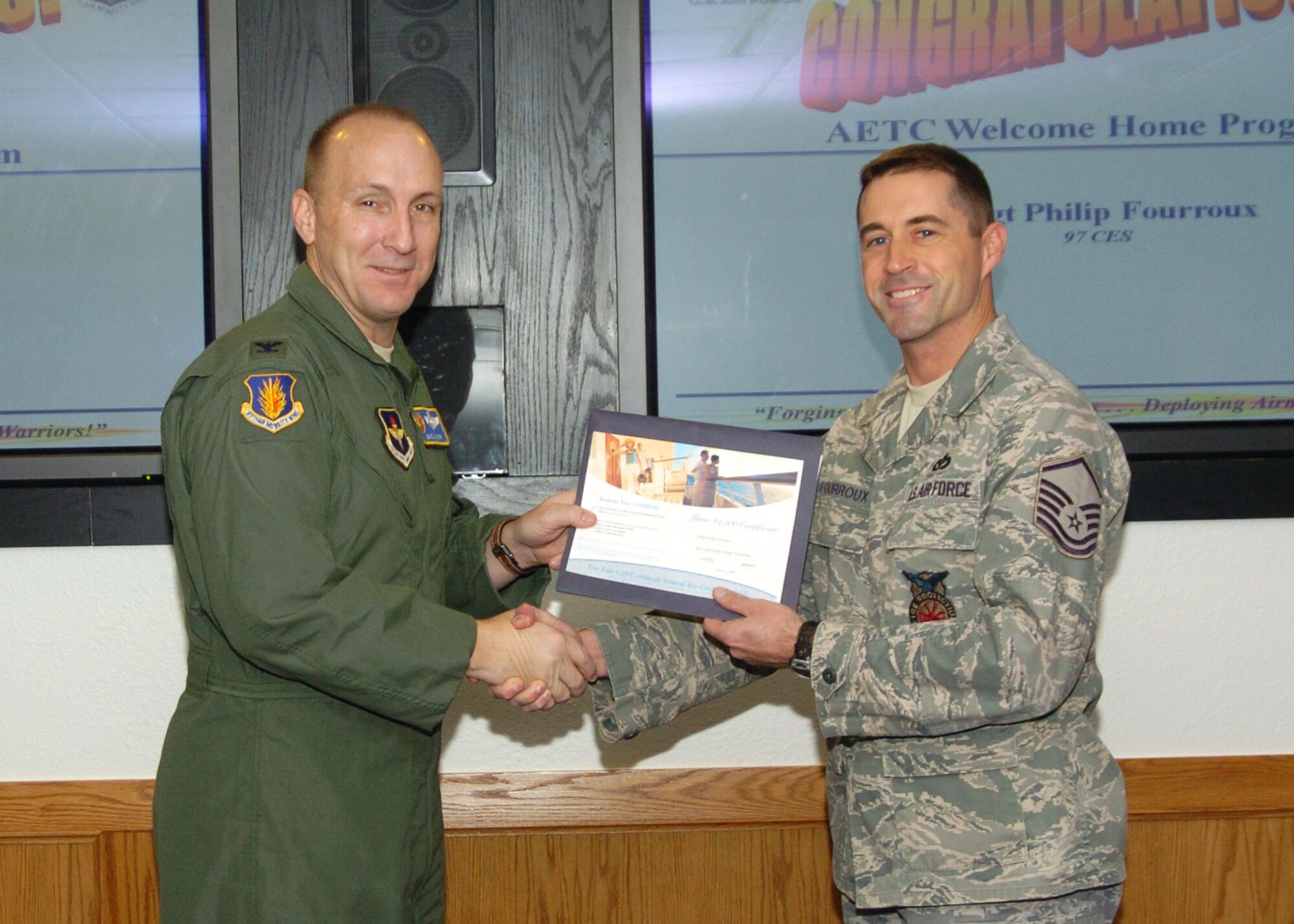 ALTUS AIR FORCE BASE, Okla.- Col. David W. Allvin, 97th Air Mobility Wing commander, presents Master Sgt. Philip Fourroux, 97th Civil Engineering Squadron, with a $2500 check from the Welcome Home Program. The program aims to provide returning deployers an opportunity to spend vacation time with their families. Master Sgt. Fourroux was one of three Air Education and Training Command winners. (U.S. Air Force Photo/Airman 1st Class Marianne E. Lane)