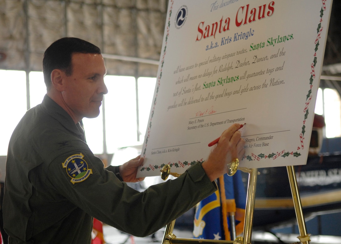 Colonel Steven Shepro, 316th Wing commander, signs a document on Dec. 18 permitting Santa Claus to use designated military airspace Christmas Eve night. The document allows Santa's mission to be successful through the use of "Santa Skylanes" without any delays in order to deliver toys to all the good boys and girls around the world. (U.S. Air Force photo by Senior Airman Melissa Stonecipher)