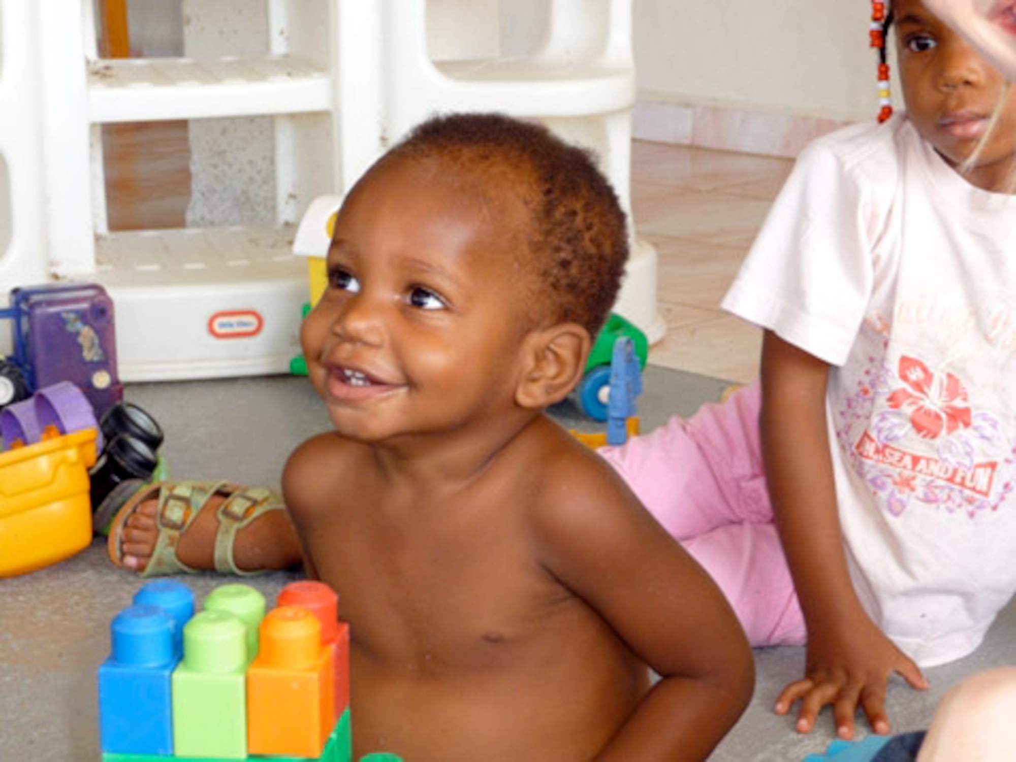 A child smiles at Airmen during playtime Dec. 12 at the Siloam Children's Hospice in Curacao, Netherland Antilles. The home for orphaned, abandoned, abused and terminally ill children has captured the hearts of 429th Expeditionary Operations Squadron Airmen as they regularly volunteer to maintain the compound's grounds, paint, donate toys and their free time to provide a safe and comfortable environment for residents. (U.S. Air Force photo/Capt. Nathan Broshear) 
