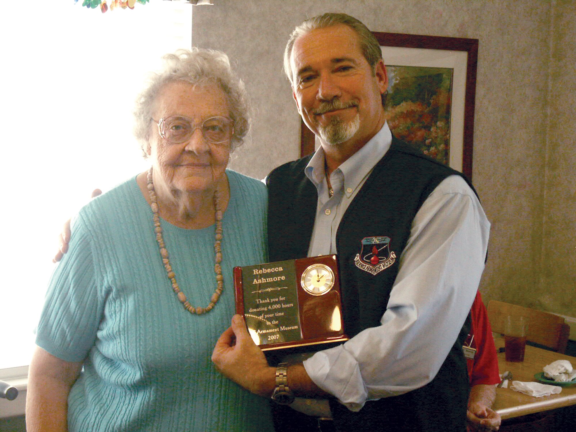 Air Force Armament Museum director George Jones awards Rebecca Ashmore with her 4000 Hour Certificate and clock engraved with her achievement.  Ms. Ashmore has been volunteering at the museum since its original opening in 1986.  (Courtesy photo.)